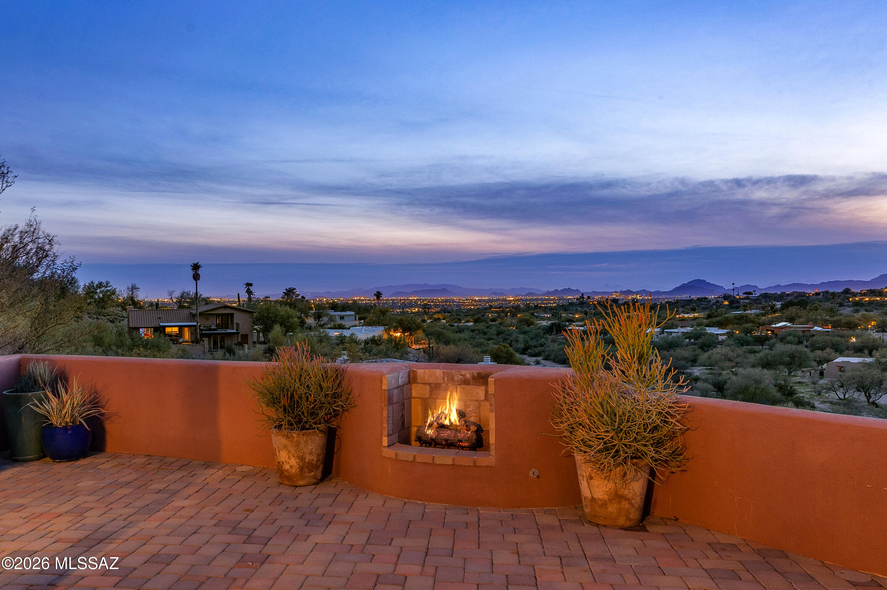Perched atop a scenic ridge in Tucson's Catalina foothills, this classic Territorial-style home delivers breathtaking panoramic mountain and city light views. Enter through a private courtyard and discover 2,143 sq ft of timeless character paired with thoughtful modern upgrades. The light-filled living room anchors the space with a custom fireplace adorned in handcrafted tile. A formal dining room and breakfast nook offer flexibility for everyday living. Relax in the private hot-tub, entertain on the private courtyard, or unwind in front of the warm fire overlooking sunsets and sparkling lights. The updated kitchen and baths, open, flowing design and tasteful updates create timeless living. Don't miss out on this stunning home sited on an elevated 0.65 acres in a quiet cul-de-sac.