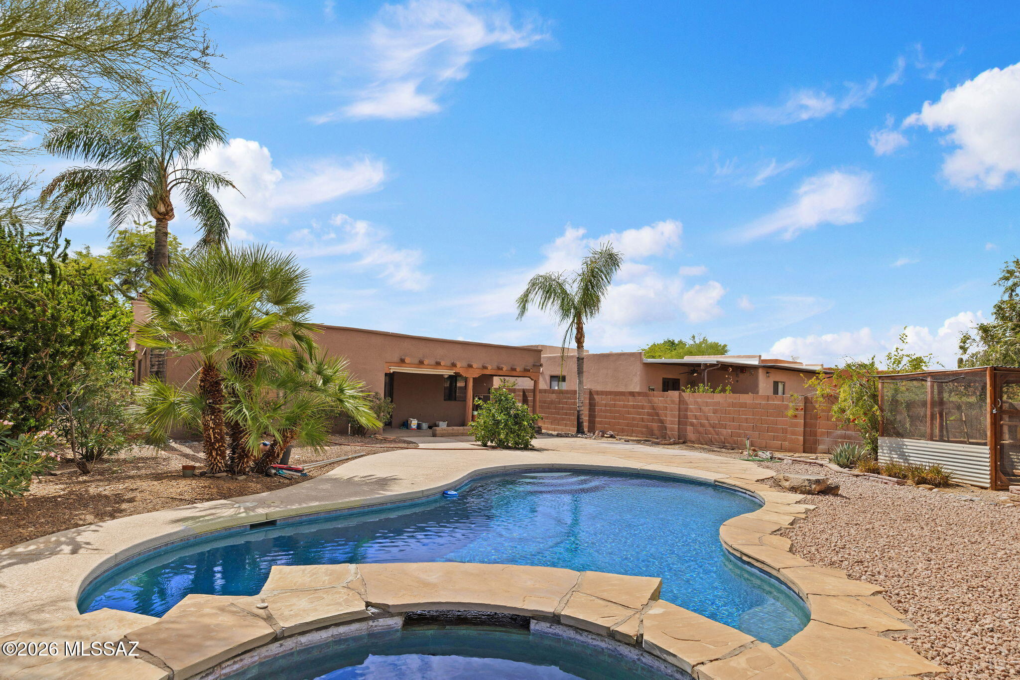 Desert Oasis awaits it's new owner. Located in quiet Ironwood Meadows, this TJ Bednar home is nearly 1400 sf, with 3 bedrooms, 2 bathrooms, and the Santa Fe charm Bednar is known for. With no neighbor behind, the back yard features a heated pool and spa, with large covered patio. East facing back yard for those warm Summer days, and some Pusch Ridge mountain views. Beautifully appointed wood beamed ceilings soar into living room, and welcome you with a kiva fireplace. Ceramic tile in a saltillo look compliments the flow of this home. open kitchen into dining and 2nd living area. Well sized bedrooms are split from Primary Owner's Suite. Call today, this home will be gone before you know it!