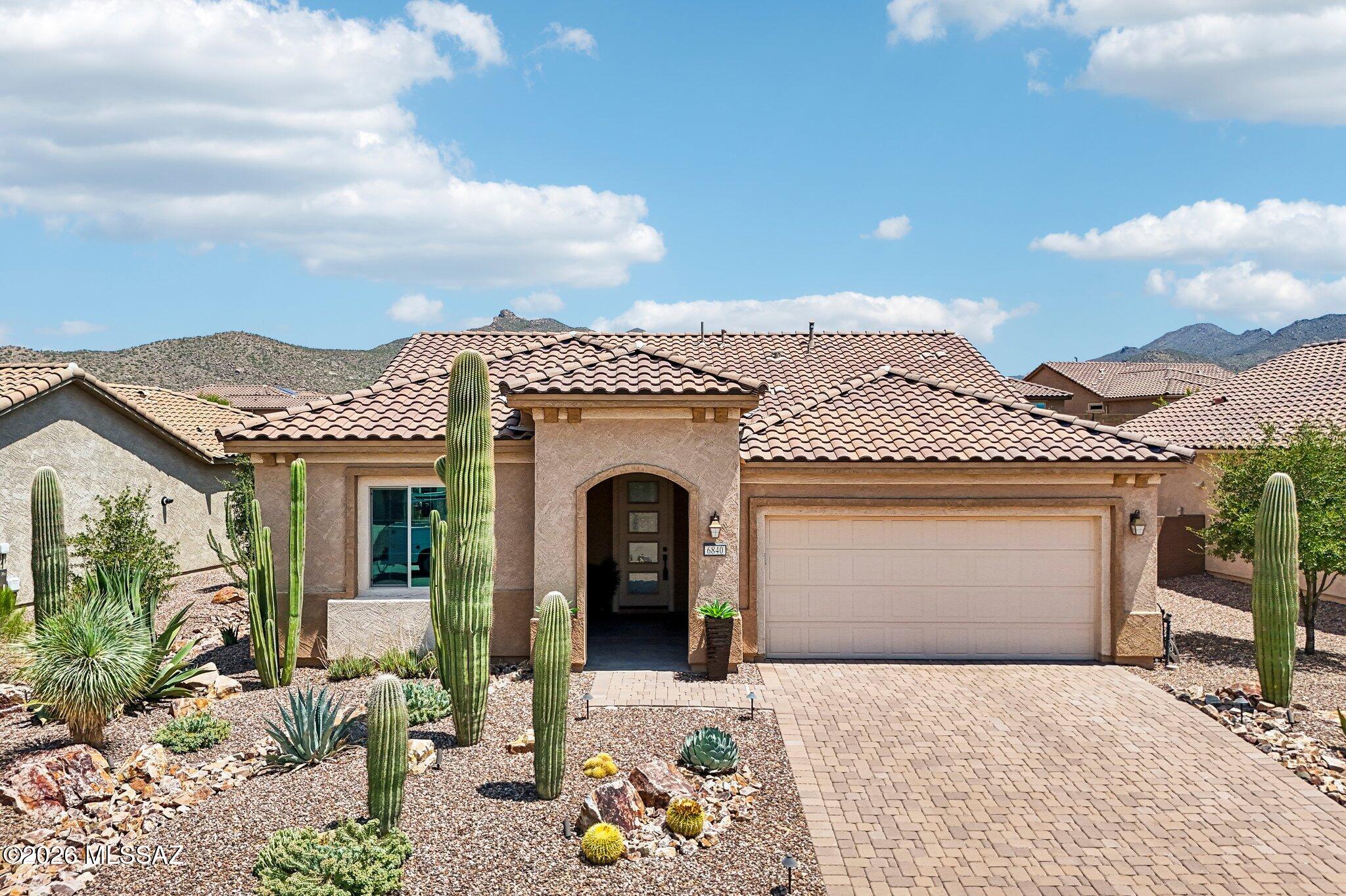Gorgeous home in the boutique style community of Del Webb at Dove Mountain steps from the Saguaro Center Clubhouse. Welcome to this beautifully upgraded Preserve model home with contemporary style finishes and a warm modern feel. You are greeted by a brick paver driveway plus multiple large saguaros in your front yard. Wonderful floorplan features 2010 sq. ft with 2 bedroom/ 2 baths + den. Open great room concept with gourmet kitchen and dining area perfect for entertaining family and friends.  Kitchen features contemporary style flat panel cabinets, quartz countertops and backsplash, ss appliances incl. 5 burner gas cooktop, custom pendants, and a curved island with seating. Upgrades throughout include ceramic tile flooring, 8' doors + double glass doors into den, remote controlled blinds, and arched doorways. Primary suite featurestray ceiling, ensuite bath with double vanities, large custom shower with bench plus professionally built-out closet. Step outside to enjoy your private backyard. Home sits on large pool sized lot with extended covered patio, outdoor stone fireplace, travertine pavers, artificial turf, professional landscaping and BBQ gas stub. This is the perfect spot to relax and enjoy year-round.  Located close to the Saguaro Center clubhouse featuring pool, spa, fitness, tennis, pickleball, and endless amenities. Don't miss this beautiful home.