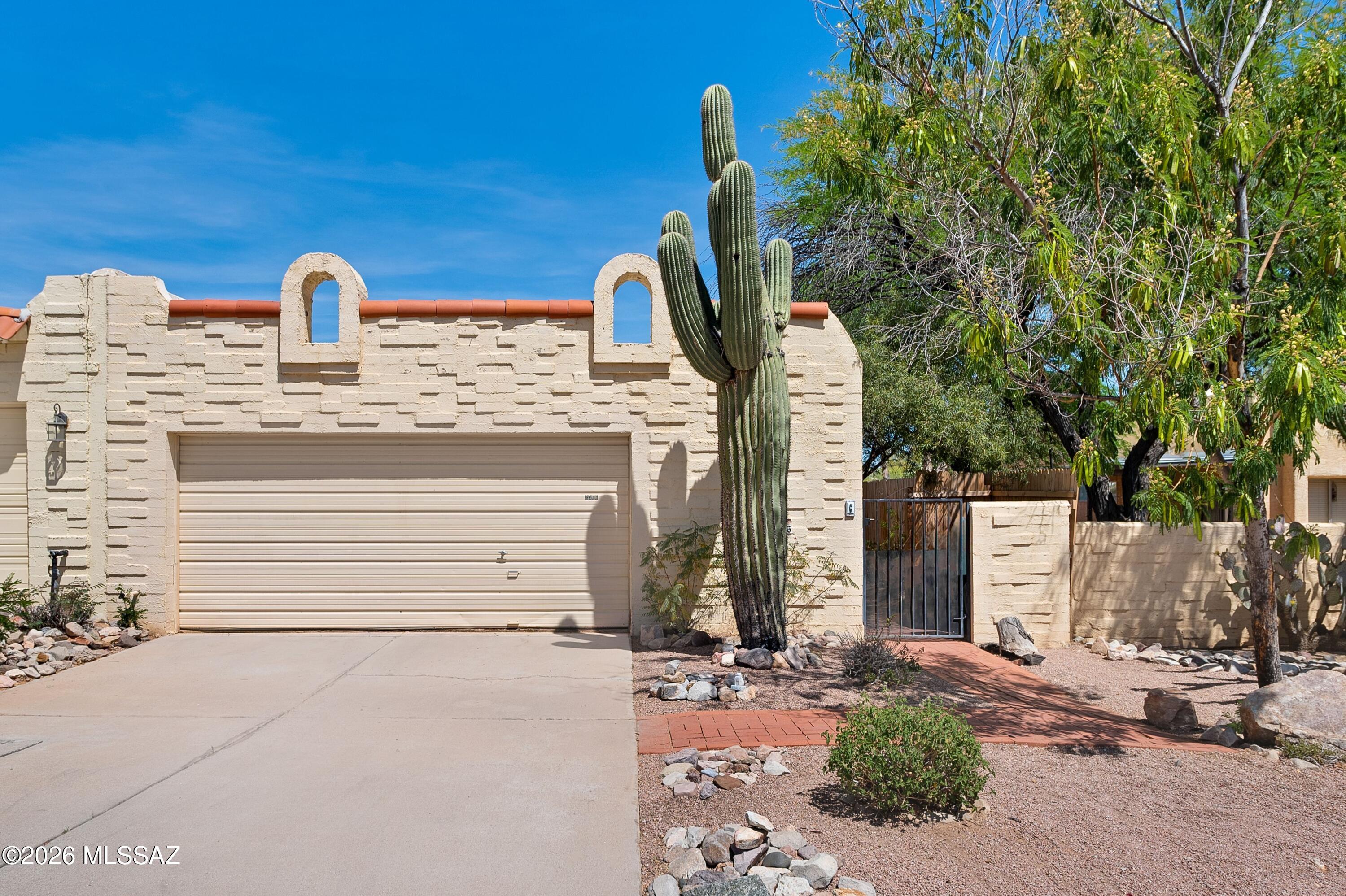 Charming 2bd/2ba townhome with versatile bonus room features classic Southwest style throughout. Soaring ceilings, skylights & abundant natural light highlight beautiful Saltillo tile floors. Spacious living room features a cozy fireplace & opens to private covered patio for easy indoor-outdoor living. Backyard features a built-in BBQ pit &  gate access to nearby community pool. Kitchen offers ample cabinetry, generous counter space + breakfast bar + newer SS appliances. Bonus room ideal for home office, den or guest space. Private primary suite opens to low-maintenance yard with mature desert landscaping. 2 car garage + storage, newer WH, and soon to be refreshed roof! Enjoy this quiet neighborhood - less than 5 miles to the U of A  + close to medical, dining, shopping & hiking.