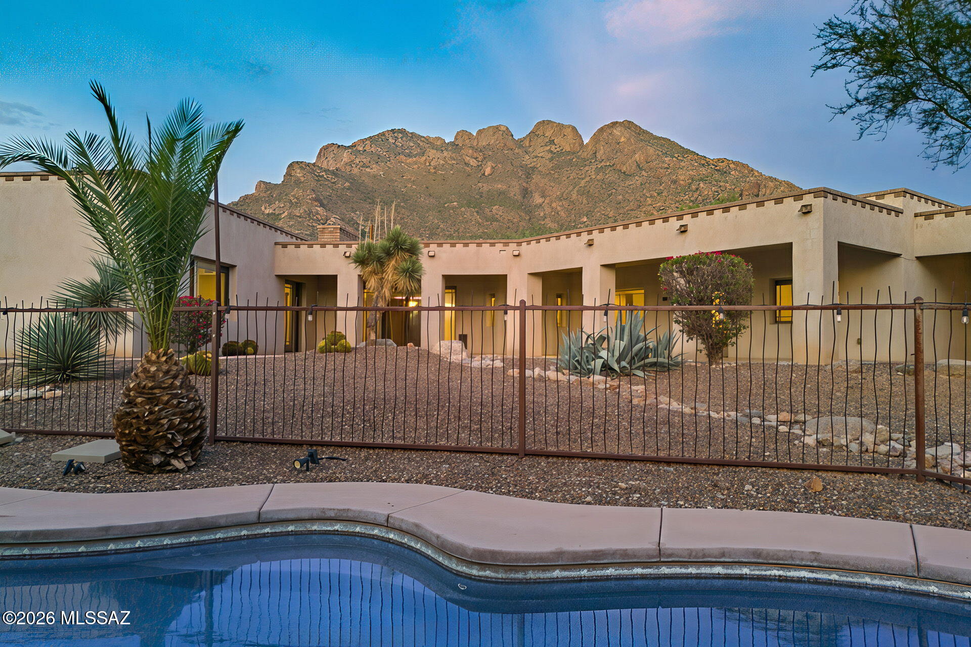 A gated courtyard creates an impressive arrival and opens to expansive interiors filled with natural light, architectural character and refined desert finishes. Scored concrete flooring, adobe brick accents, skylights and rich natural textures complement generous living, dining and entertaining spaces. The spacious kitchen features granite countertops and flows effortlessly into the home's main gathering areas, creating an atmosphere equally suited to intimate evenings and sophisticated entertaining.

Throughout the residence, authentic Southwestern architecture is elevated by a restrained, timeless aesthetic. Dramatic volumes, warm organic materials and carefully placed windows and skylights create an ever-changing interplay of light and texture, while generous living spaces unfold with n effortless sense of scale.

The connection to the outdoors is equally compelling. Private exterior spaces extend the living experience into the surrounding Sonoran Desert, offering serene settings for morning coffee, sunset cocktails and evenings beneath the Arizona sky. Mature desert landscaping enhances the sense of seclusion and establishes a setting that feels distinctly connected to its surroundings.

Spacious private retreats provide a quiet counterpoint to the home's impressive entertaining areas, while distinctive architectural details give each space its own character. Every element contributes to a residence that feels collected rather than conventional--warm, sophisticated and unmistakably Arizona.

Ideally positioned in Oro Valley, 8755 N Sunny Slope presents a distinctive opportunity for those drawn to privacy, architectural integrity and elevated desert living. More than a residence, it is a refined expression of the Southwest, where timeless materials, generous proportions and the beauty of the desert come together with effortless sophistication.