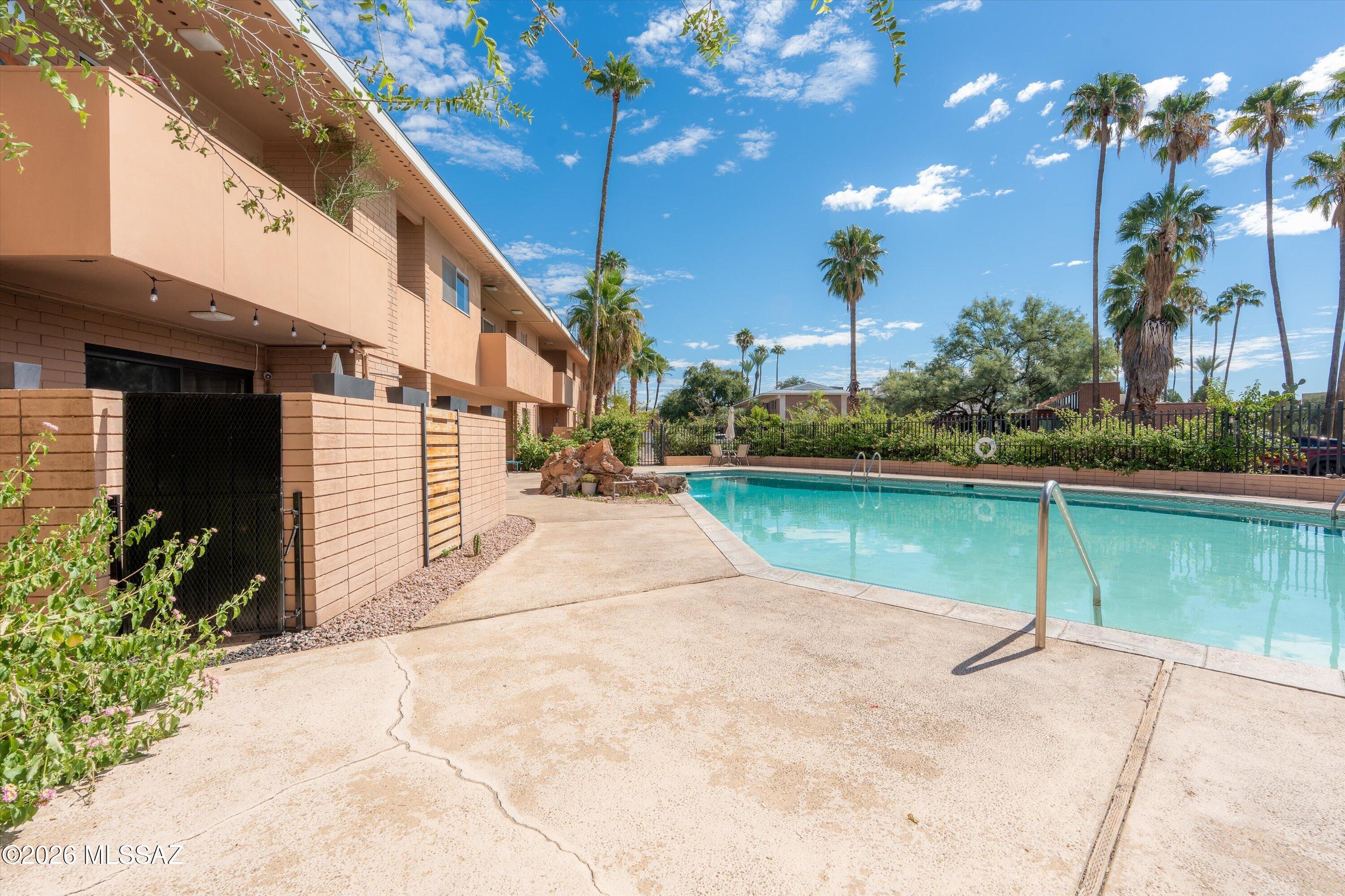 Enjoy a unique poolside lifestyle in this spacious ground floor condo! Located inside the community's gated pool area, the front door and private patio face the pool, with a private gate opening directly to the pool deck. The open layout flows from the living room to the dining area and kitchen, featuring stainless steel appliances, light wood cabinetry, laminate countertops, and tile flooring throughout. The split bedroom design offers privacy. The spacious primary bedroom includes a walk-in closet, dual vanity, lighted mirrors, and tiled shower. The hallway bath has a shower and tub, while the secondary bedroom includes a walk-in closet. A low maintenance patio, shared laundry, and assigned shared garage space. Enjoy comfort, privacy, and easy pool access in this inviting home!