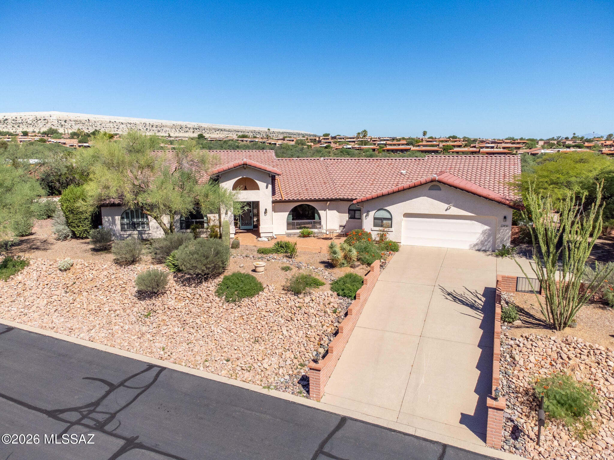 Discover the beauty of private desert living on this half-acre lot with breathtaking sunrise and sunset mountain views and no rear neighbors! This custom built home has huge windows to capture the surrounding nature, while high ceilings and abundant natural light create a bright, inviting atmosphere. An entertainer's paradise, the home offers multiple patios for seamless indoor/outdoor living, a formal dining room with buffet and convenient pull-out shelves, and a fenced yard surrounded by lush plants and mature trees. The extra-large 2.5-car garage provides exceptional space. Two bedrooms, an office, and versatile flex room offer plenty of room for guests, hobbies, and more. Tastefully designed Southwest colors make this home a true standout in a wonderfully quiet neighborhood.