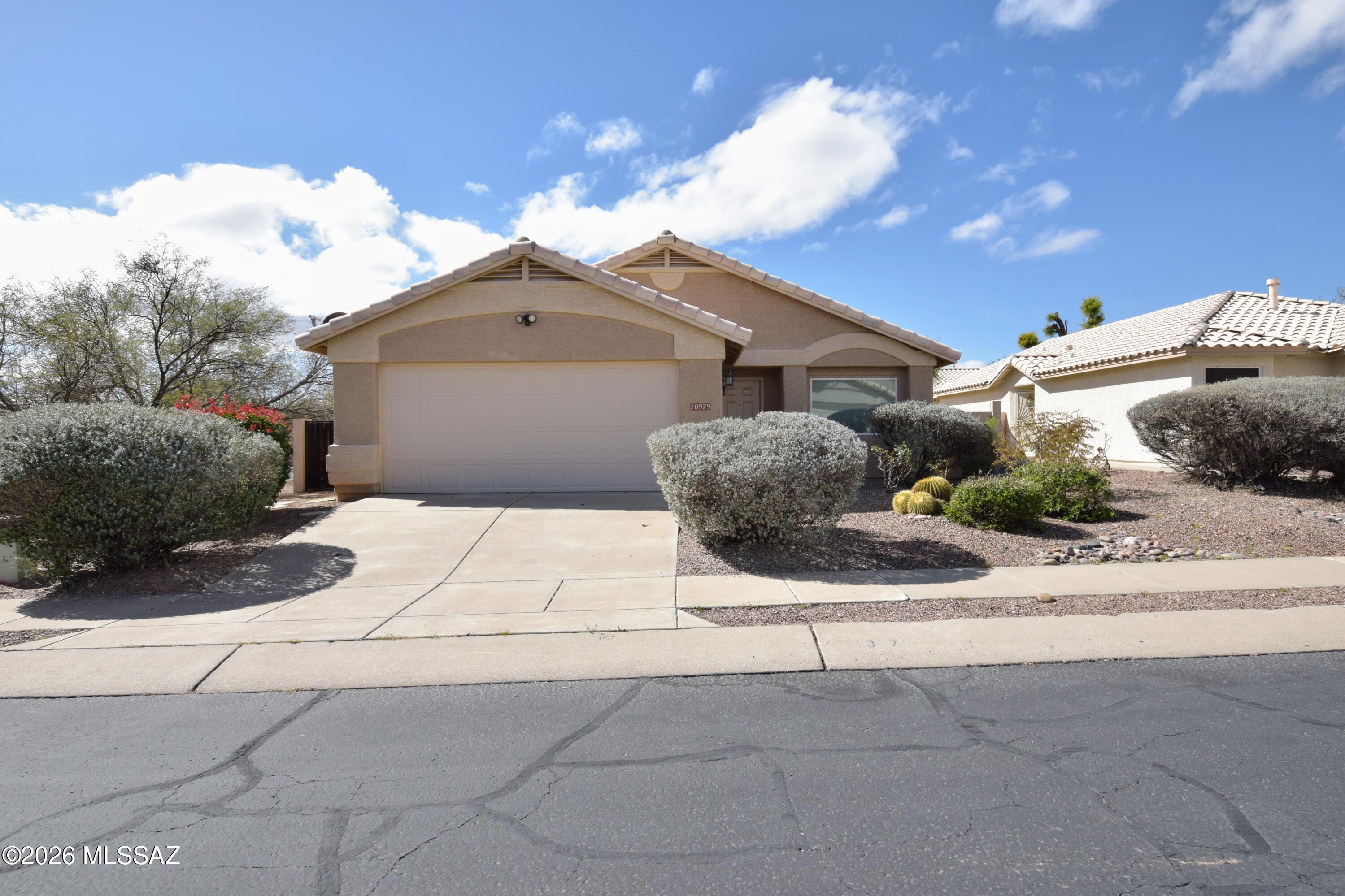 Welcome to this well-appointed 3 bedroom, 2 bathroom single-family home offering 1,650 square feet of comfortable living in a desirable Oro Valley setting. Situated on a premium corner lot with no neighbors to the south, this home provides added privacy and open space while remaining close to everyday conveniences and recreation. The dual living area floor plan offers flexibility for entertaining, working from home, or relaxing, and tile flooring throughout enhances durability and easy maintenance. The kitchen features granite countertops, a breakfast bar, and ample workspace, making it ideal for both casual meals and hosting guests. Central air conditioning and central heating ensure year-round comfort, while washer and dryer hookups add everyday convenience. The spacious primary suite includes a walk-in closet and private access to a lush backyard with mature landscaping and a red brick patio, creating a peaceful retreat. The primary bathroom is thoughtfully designed with a dual sink granite vanity and a separate garden tub and shower. A two-car garage provides secure parking and storage. Located near the El Conquistador Golf Course, Tennis, and Fitness Center, this home offers easy access to outdoor recreation, walking paths, and scenic surroundings, making it an excellent choice for those seeking comfort, privacy, and an active Tucson lifestyle. This home is offered to