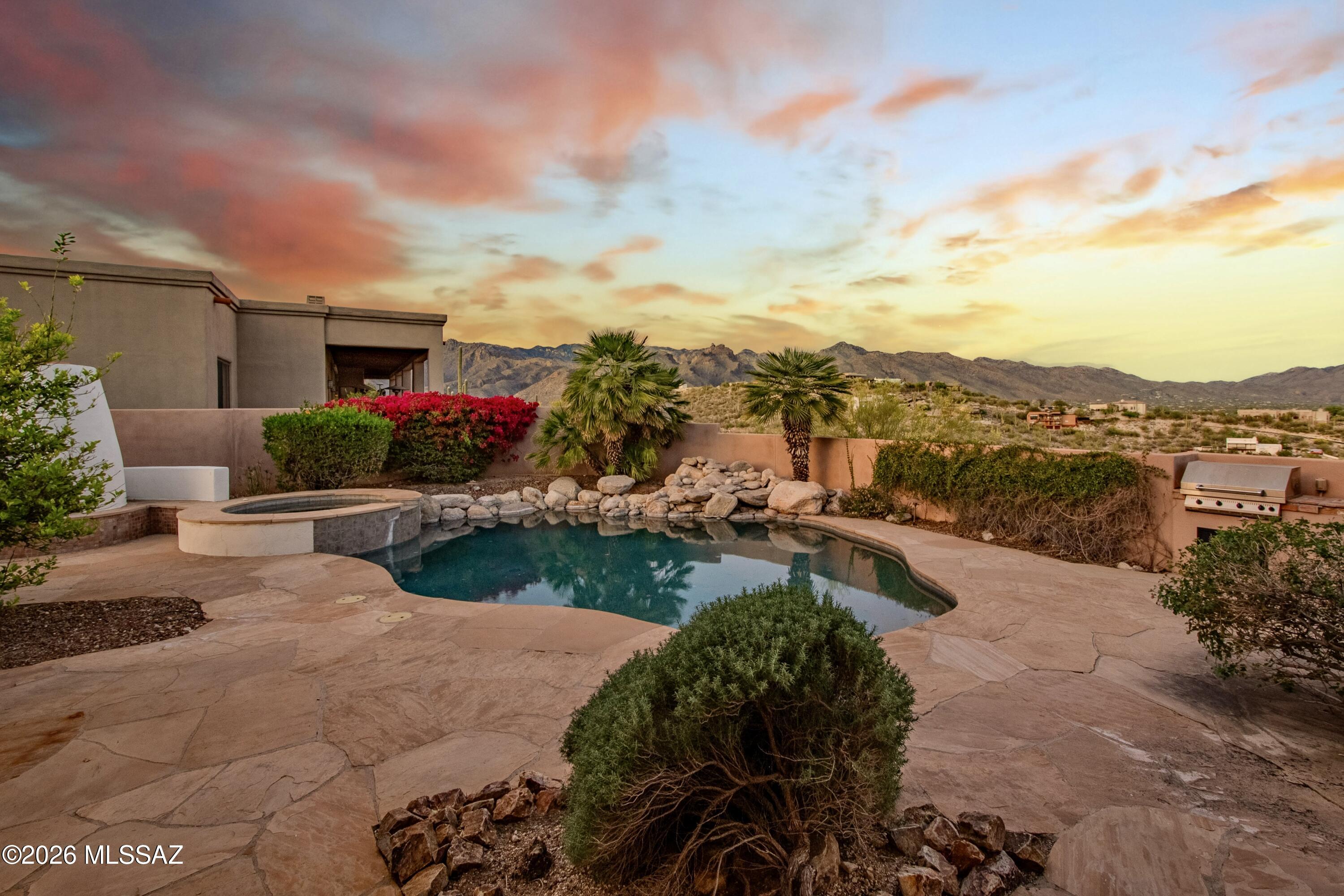 Elevated on a premier ridge-top homesite, this exceptional residence in Sabino Mountain offers a rare combination of privacy, architectural integrity, and truly breathtaking, unobstructed panoramic mountain views. Set on 1.14 acres within one of Tucson's most coveted gated enclaves, distinguished by its dramatic setting and rare neighborhood sidewalks.
Built in 2001 and thoughtfully positioned to capture the surrounding beauty, the home embodies timeless contemporary design with a seamless, easy-living single-level layout. From the moment you enter, the foyer frames sweeping views through the expansive great room, where soaring ceilings, gallery walls, and artful niches are filled with natural light. The ideal split-bedroom floor plan ensures both comfort and privacy, complemented by solid wood paneled doors, expansive tile flooring, and architectural details throughout.
Designed for everyday living and effortless entertaining alike, the kitchen is a standout centerpiece. Anchored by a central island and surrounded by expansive granite surfaces, it features custom cabinetry with pull-outs, display shelving, and integrated lighting. High-end appliances include a Jenn-Air commercial gas range with hood and heat lamps, double-wall ovens, and an Advantium microwave. A beverage bar with a built-in chiller enhances entertaining, while both casual and formal dining spaces, complete with a coffered ceiling and a built-in buffet, offer versatility.
The desirable east-facing backyard invites year-round enjoyment with a large covered patio, flagstone hardscape, a heated Pebble Tec pool and spa with a spillway water feature with a newer pump and filter (2023). A charming kiva fireplace anchors a separate niche patio, creating an intimate space. Mature, lush desert landscaping, enhanced by a new drip system (2025), surrounds the fully fenced yard, offering both beauty and ease of care.
The owner's suite is a peaceful retreat, opening directly to the patio and featuring a 5-piece bath with a garden tub, walk-in shower, and a customized closet system. Spacious secondary bedrooms provide flexibility, including one with private access to a hall bath. A well-appointed den, complete with a stately library cabinet and patio access, offers the option of a 4th bedroom, a recreational space, or an office.
Additional highlights include an inviting covered entry, a gently sloped, extended driveway, a spacious three-car garage with 8-foot door headers, and a large, light-filled laundry room with workspace, storage, and a built-in desk, perfect for hobbies or organization.
Ideally located near Sabino Canyon Recreation Area and Ventana Canyon Resort & Country Club, residents enjoy immediate access to world-class hiking, cycling, golf, tennis, and pickleball, as well as premier dining, shopping, and top-rated schools.
Lovingly maintained by its long-term owner, the home features a new roof and sealed parapets (2026), along with recent updates to low-E glass and window seals.
This is a rare opportunity to own a view property of this caliber in one of Tucson's most sought-after foothills communities.