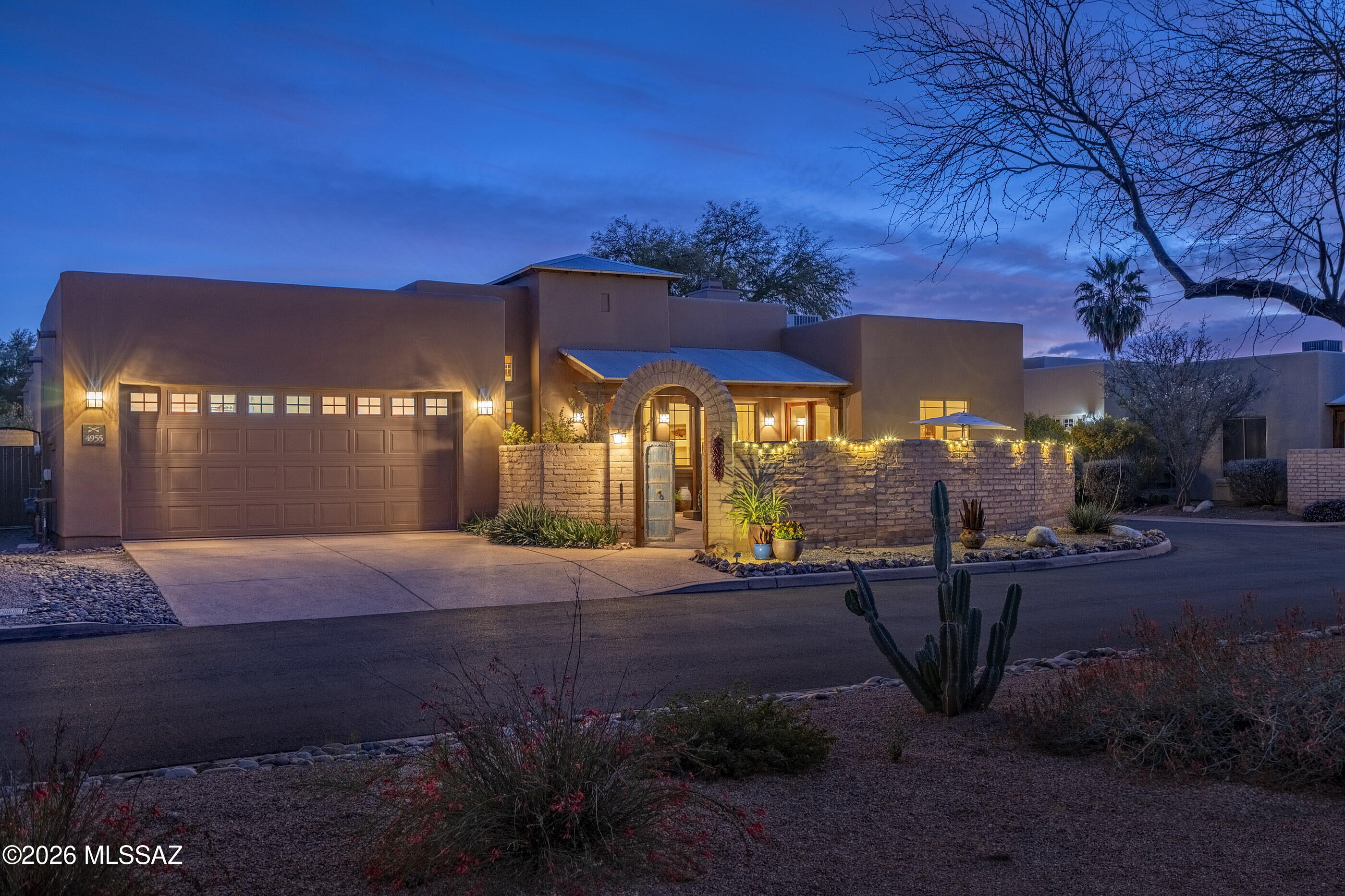 Situated within the gated enclave of The Garrison in the Old Fort Lowell Historic District, this architecturally compelling territorial residence offers a rare combination of privacy, authenticity, and elevated desert living. A graceful arched entry introduces a private, walled front courtyard, immediately establishing a sense of arrival. Surrounded by warm masonry walls and layered desert landscaping, the courtyard is designed as an intimate outdoor gathering space, complete with ambient lighting and a covered north facing veranda. This area serves as both a retreat and a refined prelude to the interiors beyond. Inside, the home reveals dramatic scale and architectural character. Soaring ceilings articulated by exposed wood vigas create volume and visual interest, while clerestory windows draw in natural light with intention. Stained concrete floors extend throughout, grounding the residence in a modern sensibility that complements textured and neutral-toned walls with softly sculpted corners. The Great Room unfolds as the central gathering space, seamlessly connecting living and dining areas. Expansive picture windows and glass doors frame courtyard views and reinforce the effortless indoor outdoor flow that defines the property.

The kitchen is both striking and functional, anchored by solid wood cabinetry, slab granite countertops, and a diagonally set porcelain  backsplash. A professional grade stainless steel gas range and hood command attention, complemented by premium appliances and a generous peninsula with an integrated sink and bar seating. A built-in desk provides additional versatility while maintaining a cohesive design narrative.

The bedroom wing is thoughtfully arranged for privacy and flexibility. The office or third bedroom features custom built-in wood cabinetry with an integrated Murphy bed, allowing the space to transition seamlessly between executive office and guest suite. French glass doors open directly to the front courtyard, enhancing its connection to the outdoors. On the southwest end of the residence, the primary suite offers generous proportions, soft southern facing natural light, and direct access to the rear patio. The spa inspired bath is appointed with a soaking tub set within a tiled surround, a separate glass enclosed shower with decorative tile detailing, dual vanities, and expansive counter space. On the southeast end, the guest bedroom provides comfortable separation and is paired with a beautifully finished ensuite bath with coordinated tile work and elevated finishes.

At the rear of the home, the primary entertaining courtyard unfolds as a dynamic outdoor living environment. Brick paver patios, raised planters, banco seating, and multiple lounge and dining areas create a layered, resort like setting, with curated landscaping and soft string lighting elevate evening gatherings. Seamlessly connected to the interior through generous glass openings, this outdoor sanctuary becomes a natural extension of the home, embodying the sophistication and ease of refined desert living.