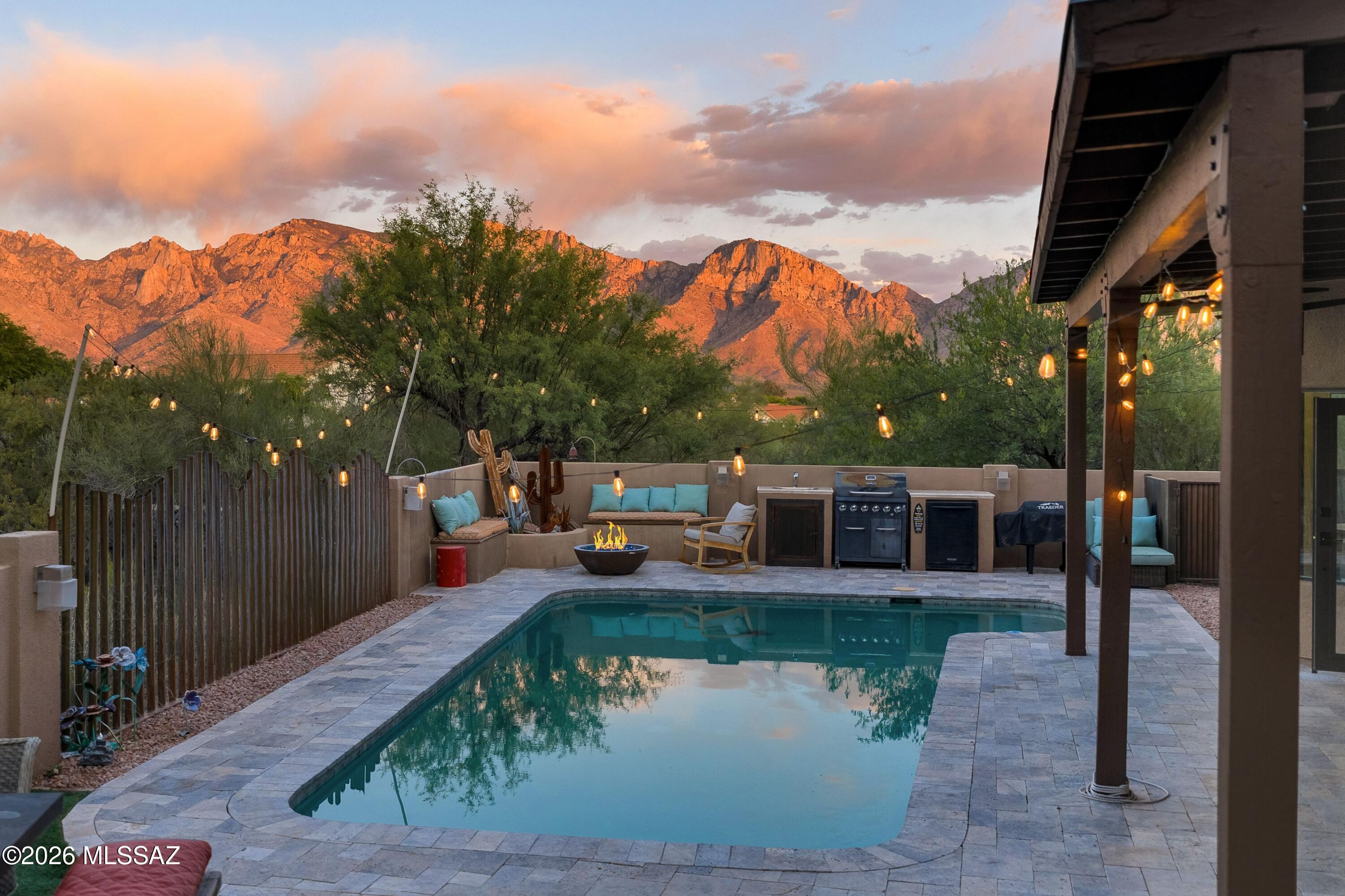 Set on a private corner homesite with spectacular Pusch Ridge views, this completely renovated five-bedroom home offers the rare combination of exceptional privacy, refined finishes, and resort-style outdoor living in highly desirable Rancho Vistoso in Oro Valley. Bordered by common areas with mature trees on three sides with no immediate neighbors, the setting feels remarkably secluded while remaining very convenient.
A paver-lined front courtyard and recessed entry framed by a custom wrought-iron front door create a memorable arrival. Inside, dramatic ceilings, expansive windows, and large-plank bamboo flooring fill the home with natural light and warmth. The living room is anchored by a striking floor-to-ceiling tiled fireplace..Continued... while the spacious dining area includes custom wine storage designed for effortless entertaining.
The remodeled kitchen opens seamlessly to the great room, where a beehive fireplace with copper accents adds architectural character. A large glass door opens the back wall directly to the covered patio and frames panoramic mountain views, creating an effortless indoor/outdoor connection. Designed for both entertaining and everyday living, the chef's kitchen features custom cabinetry and hutches, granite countertops, a large island breakfast bar, stainless steel appliances including a gas range and built-in refrigerator, microwave with air fryer functionality, and a walk-in pantry with custom shelving. A bright breakfast nook overlooks the pool and mountain views beyond. Powder room conveniently located just off the great room.
The spacious primary suite is located downstairs and features dual walk-in closets, patio access, and a beautifully renovated bath with a custom tile shower, dual-sink vanity, and soaking tub positioned beside a fireplace. Upstairs, the home theater with kitchenette and ensuite bath could be a second primary suite or flexible guest retreat. Three generous-sized additional bedrooms and a hall bath complete the upper level.
The resort-style backyard is designed to take full advantage of the dramatic Pusch Ridge views. Covered patio lined with travertine pavers wrap around the Pebble Tec pool, while the outdoor kitchen, built-in banco seating surrounding a gas fire feature, and low-care artificial turf create multiple spaces for entertaining or enjoying time with family and friends.  The hot tub is perfectly positioned to capture unobstructed Catalina Mountain views and spectacular Arizona sunrises.
Additional features include a heated and cooled oversized three-car garage with metal garage doors, spacious laundry room with extra storage, newer HVAC systems, newer windows, 9-foot upstairs ceilings, and a new roof installed in 2023.
Located near parks, libraries, the Oro Valley Aquatic Center, community recreation center with golf, tennis, and pickleball, Catalina State Park, and convenient access to Interstate 10 and Sky Harbor Airport. Close to shopping, restaurants, Trader Joe's, Whole Foods, and several world-class golf courses, with excellent public, charter, and private schools nearby. The elementary school for this house is Painted Sky, ranked the #1 Elementary School in Oro Valley.
