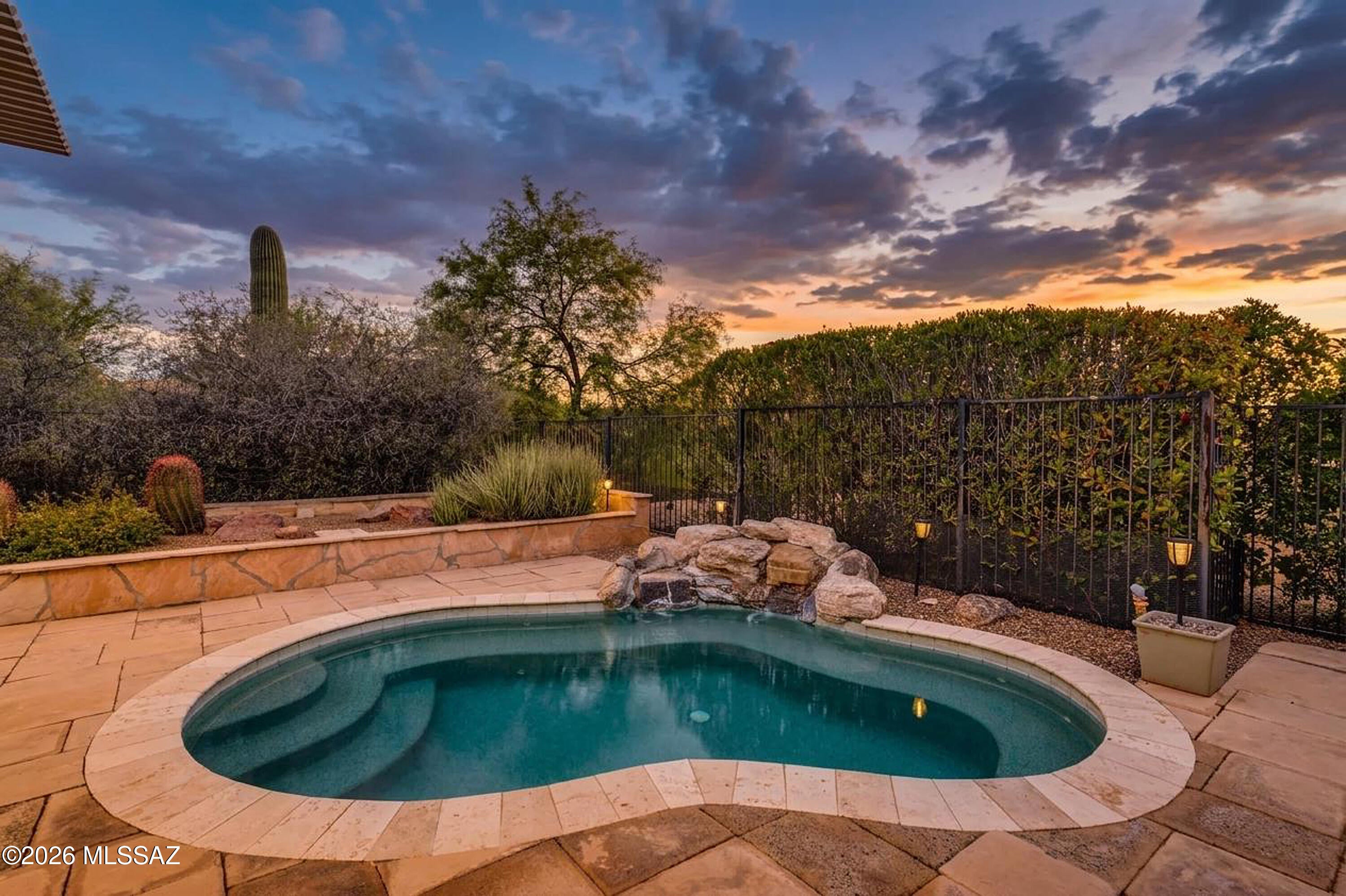 Situated on a premium homesite backing to lush common area, this 1,589 sq.ft. Oakmont model in Quail Creek features a spacious backyard retreat designed for year-round Arizona outdoor living, complete with a refreshing spool and tranquil waterfall feature. This home offers 2 BR, 2 BA, and a versatile den ideal as a formal dining room, home office, or hobby space. A welcoming front paver courtyard leads to the entry foyer and into a spacious great room designed for comfortable everyday living and entertaining. Hard-surface flooring extends throughout the living areas, while both bedrooms feature new carpet for added comfort. The upgraded kitchen showcases granite countertops, pot drawers, pantry closet, electric range, dining nook, and a built-in buffet providing additional storage and serving space. The extended owner's suite features a bay window overlooking the spool and includes a well-appointed bath with dual vanity, tile shower, and walk-in closet with custom built-ins. A split bedroom plan offers privacy for guests, with the guest bedroom featuring a built-in armoire and adjacent bath with tub/shower combination. The backyard is designed for relaxed resort-style living with an extended paver patio, oversized pergola, and the versatile spool and tranquil waterfall feature combine the best elements of a spa and pool. Ideal for cooling off on warm Arizona days, enjoying soothing hydrotherapy, or simply unwinding outdoors, this inviting space is perfectly suited for both quiet relaxation and entertaining family and friends.