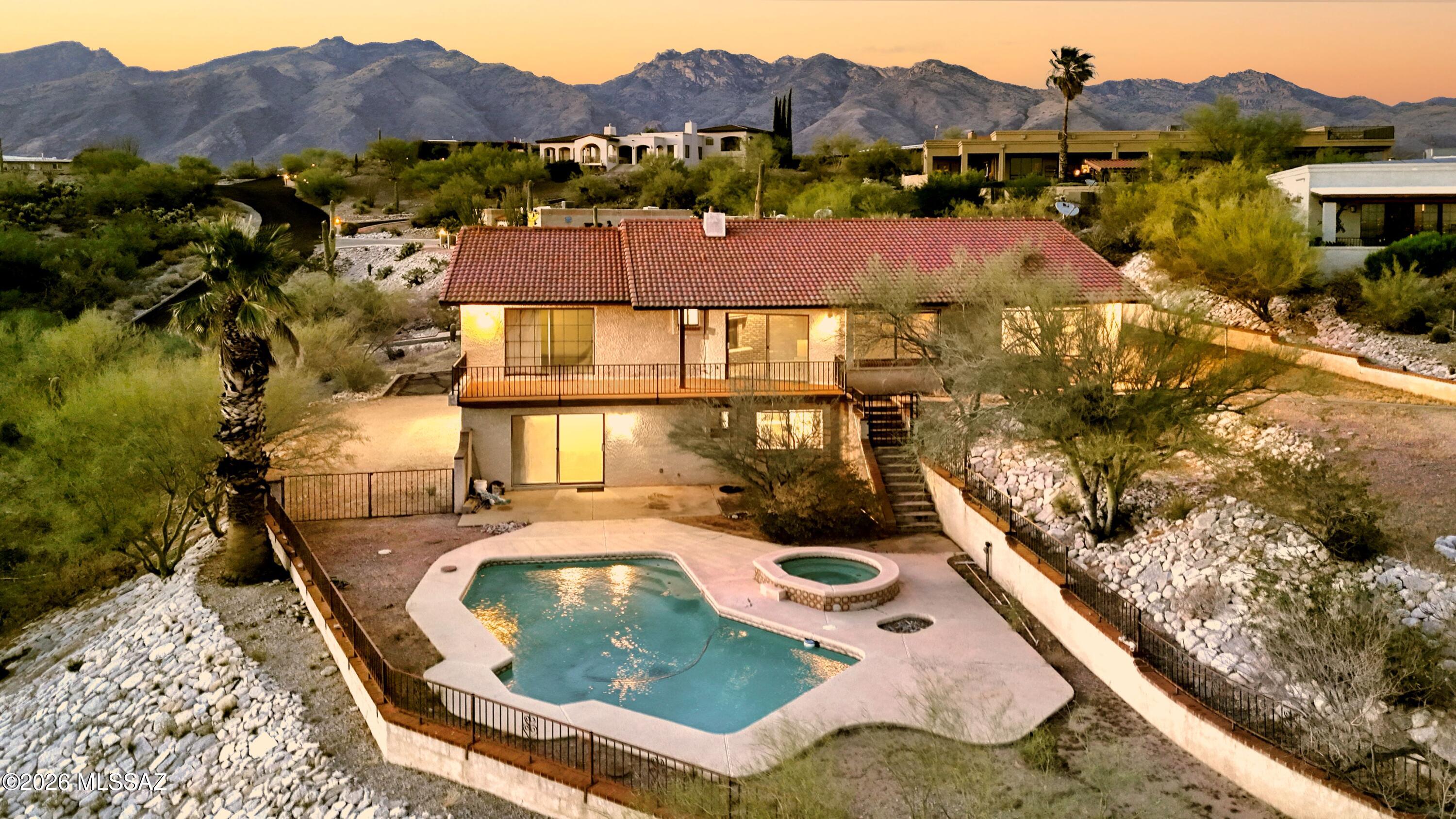 Perched on an elevated lot, this home captures the Phenomenal City Light Views that make the Foothills so sought after. Stately saguaro welcomes you as you arrive, setting the tone for the stunning scene. Inside, the living room features a wood-burning FP & slider to a viewing deck where the sparkling skyline takes center stage. Kitchen offers an island w/elec cooktop, brkfst nook w/banquette & pass-thru to the dining rm. Primary offers ensuite w/WI shower. 3 addl bdrms plus office/den for flexible living. 1 bdrm & bath are located downstairs. Outdoors enjoy the pool, lrg side yard, 2-car gar & 2-car crpt. Bring your ideas & make this property your own with these stunning views and upside potential. Lot 129 (0.69 ac) is available for $100k with an acceptable offer on the home.
