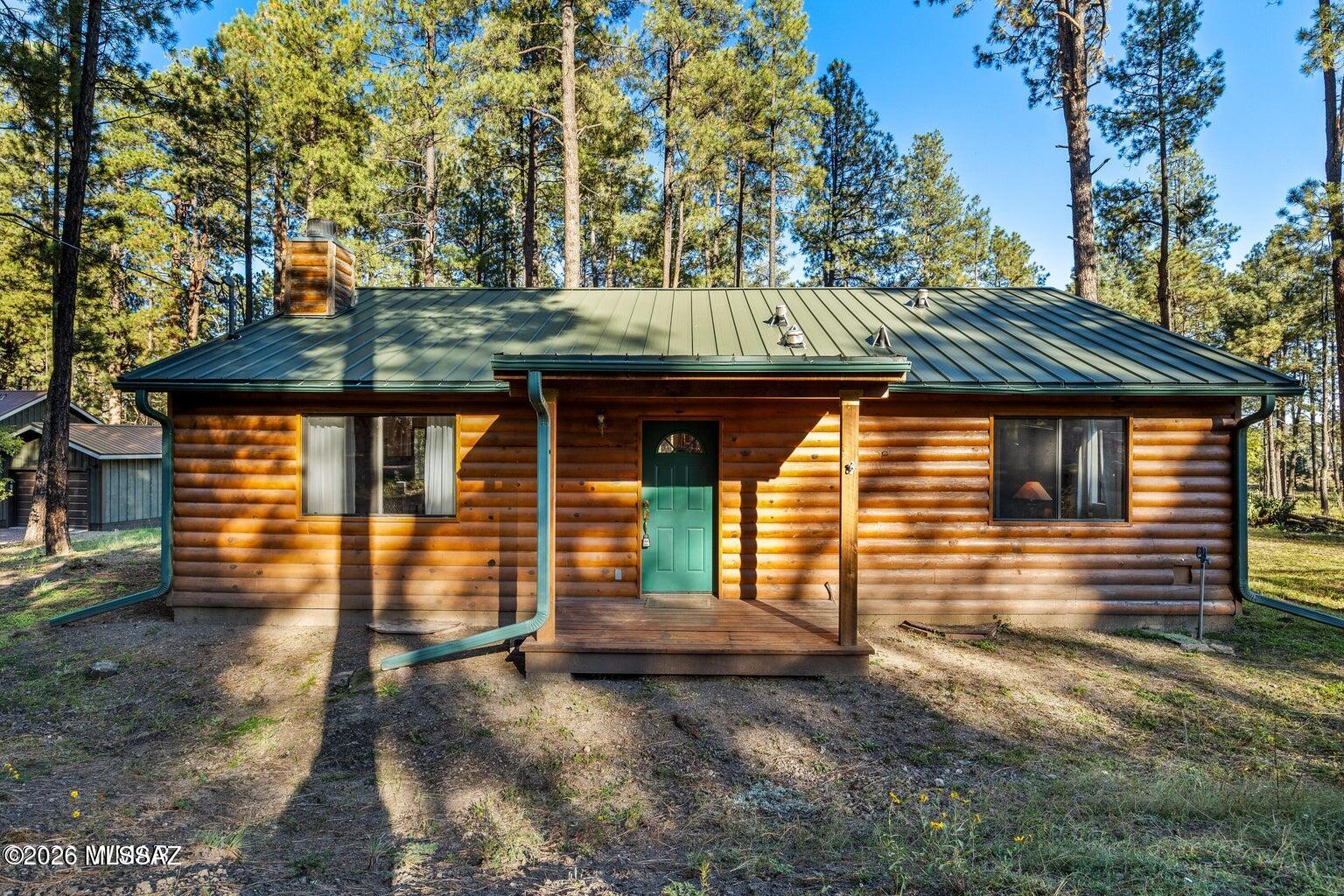 Tall pines, mountain charm, and no HOA--this custom two-bedroom, two-bath cabin offers the perfect Alpine escape. Escape to the pines with this charming log-sided cabin in Alpine Village East, where easy year-round access and no HOA make mountain living even sweeter. Situated on a half-acre lot, this approximately 1,200-square-foot home offers two bedrooms, two full bathrooms, and an open, airy great room with vaulted ceilings and generous windows that fill the interior with natural light. Beautiful wood floors and a custom wood-burning fireplace with a hearth create a warm, inviting atmosphere. Central heating and air conditioning provide comfort throughout the seasons--a welcome bonus in Alpine! The kitchen features custom hickory cabinetry, natural stone countertops with a coordinating backsplash, a spacious pantry, built-in microwave, and an island offering additional storage. A separate dining room provides space to gather, while both bathrooms feature natural stone countertops and coordinating backsplashes.
French doors open to a covered patio, perfect for relaxing and enjoying the surrounding pines. A pitched metal roof with rain gutters adds practical appeal. Conveniently located near local amenities, yet tucked away enough to enjoy a peaceful mountain setting, this cabin is ideal for year-round living or seasonal adventures. Explore the hunting, fishing, hiking, and biking opportunities that make Alpine special, with Sunrise Park Resort within reach for winter recreation and summer fun.