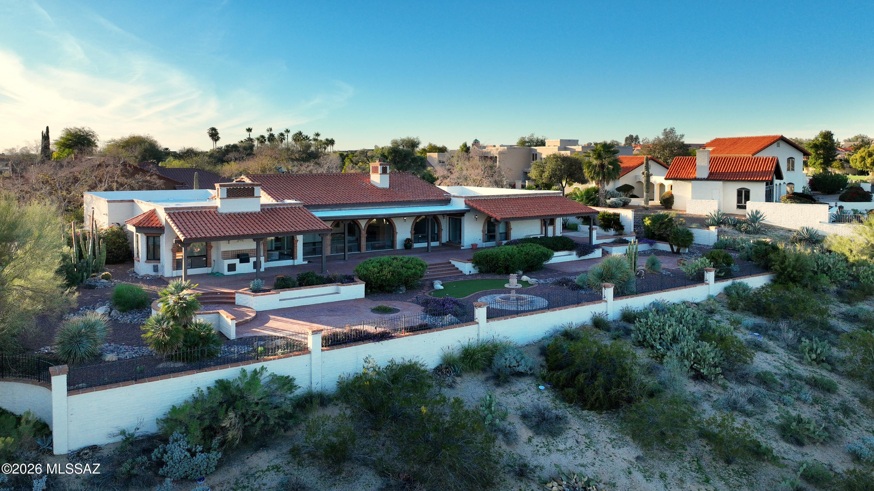 Spacious territorial retreat perched on .75 acre lot commands sweeping panoramic mountain & valley views. Timeless SW & Spanish Colonial design shines thru beamed ceilings, brick arches & 3 fireplaces (a shared between living spaces). Designed for effortless entertaining, the expansive living room centers on a dramatic fireplace. Generous kitchen offers granite counters, oversized prep island, abundant cabinetry & opens to dining room warmed by its own fireplace. Serene primary suite features walk-in closet, dressing area, clawfoot soaking tub, dual sinks & separate shower. Two guest suites enjoy ensuite baths. Den w/fireplace & custom built-ins + 4th bedroom w/ private sauna add versatility. Extensive covered patios & vast backyard create an elevated desert escape above the Tucson valley
