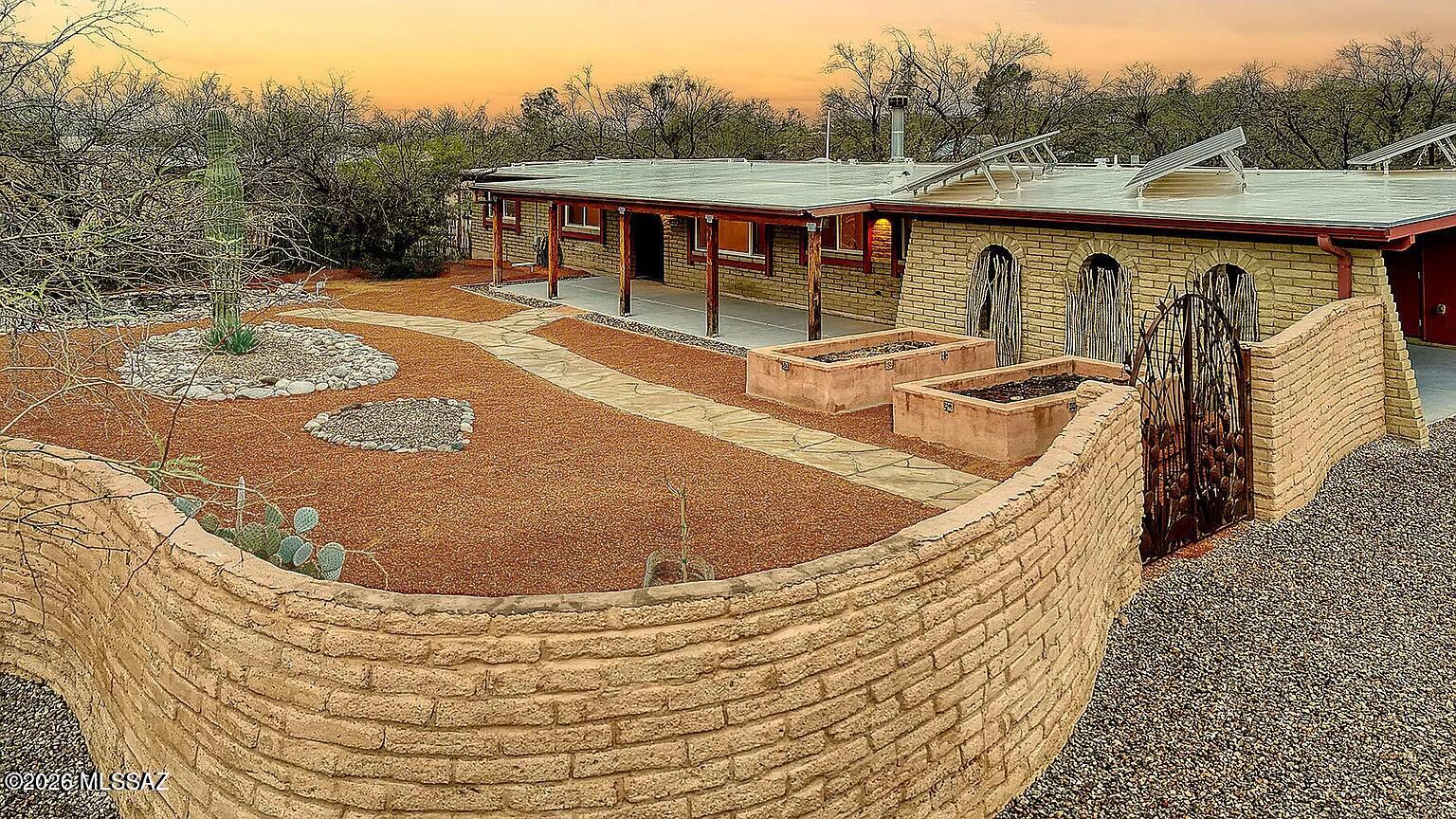 Lovingly maintained and upgraded masonry, Tres Lomas home on a .90 wooded acre in tranquil Bear Canyon. Remodeled & expanded Cook's kitchen w/ large butcher block center island, ample storage, upgraded bathrooms renovated in 2014 with top-quality fixtures in a design that is modern yet warm and inviting. Fall in love with the expansive and private backyard with its abundance of shade trees and 2000 sq ft of hardscaped entertaining space. Enjoy relaxing on your front porch while listening to the waterfall in your pond.  This property has many outstanding features that make it a rare gem, including custom hardwood doors, Dual pane windows, colored concrete floors, a two-sided fireplace, 2 kW of solar power, a rainwater harvesting system, a spa to warm you on cold winter nights, 2 workshops, RV parking with power supply, masonry walls around nearly the entire property, and plenty of room to build a casita that would be well-separated from the main house. Walking distance to one of the best parks in greater Tucson. 2 car carport.