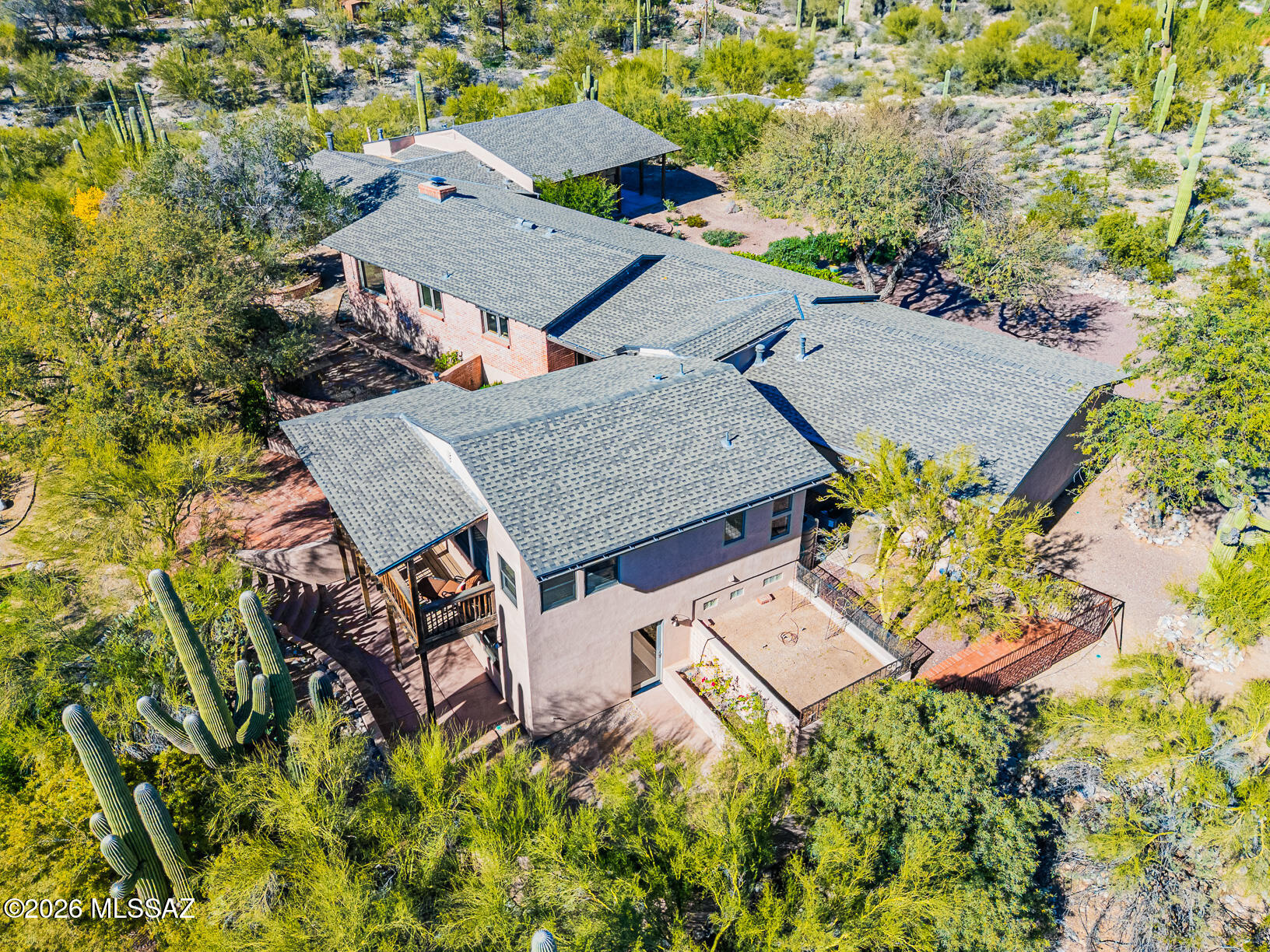 Central Foothills private hilltop location w/mtn, city & sunset views. The original home was Joesler-approved and stamped, and then greatly improved & expanded in 2006 to a 4BR, 4BA home (3904 sq ft), maintaining much of the original Joesler character & charm, including red concrete floors, exposed brick, mahogany walls, box-beam ceilings, & a large fireplace. Huge flagstone patio & covered Ramada overlooking this saguaro-studded lot. Split 2/2-bedroom plan with private guest quarters, including a private entrance, lends itself to flexible use for multi-generational families, student quarters, guests, home office, caretaker quarters, etc.  Take a walk through the exceptional grounds that cater to wildlife & natural desert enthusiasts, complete w/multiple water catchments.