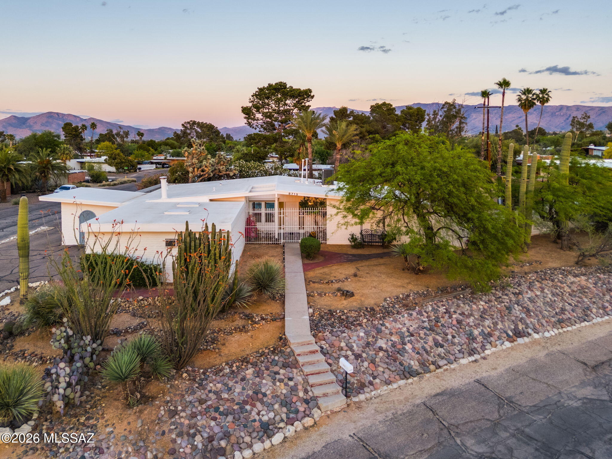 Mid-century lovers-this is the one! Positioned on a premier elevated lot within Windsor Park, this residence captures Catalina Mountain views, striking sunsets, and a setting that feels both private and expansive. Windsor Park is recognized as one of Tucson's most significant mid-century neighborhoods, known for its intentional design and preserved architectural character. The home reflects that legacy with tongue and groove ceilings, exposed beams, and rich wood cabinetry. Designed to maximize light and views, homes by J. Herbert Oxman are known for expansive glass - if unfolded, offering over 500 SQFT of view. That design is felt throughout, with natural light pouring into the main living spaces and a strong connection to the outdoors. The kitchen serves as a natural gathering space, anchored by two peninsulas with bar seating. A large kitchen bay window over the sink frames Catalina Mountain views and fills the space with natural light. Thoughtful storage includes pull-out shelving and lazy-susan cabinetry. The bedroom wing features generously sized rooms, each with sliding glass doors that open directly to the backyard. Both bathrooms have been updated with timeless finishes. Recent improvements include a 3 year old roof and 4 year old HVAC and water heater. The home features tile throughout. The living room includes security shades for added privacy, while the gated front courtyard offers a true lock-and-leave setup. Outdoor spaces are well designed and easy to enjoy. The backyard is centered around a large pool with mountain views. A north-facing patio off the kitchen provides a quiet, shaded retreat and extends the living space outdoors. Additional features include multiple storage structures and a spacious garage with built-in shelving. Windsor Park offers a rare combination of character and community. There is no HOA, but it has a recognized tight-knit neighborhood association that is pursuing a historical designation. The neighborhood layout follows the natural topography and was designed to capture views throughout. Residents gather annually for a neighborhood block party, yard sales, or to just use the new lending library. Come experience this mid-century residence in one of Tucson's most meaningful historic neighborhoods. (Neighborhood roads scheduled to be repaved).