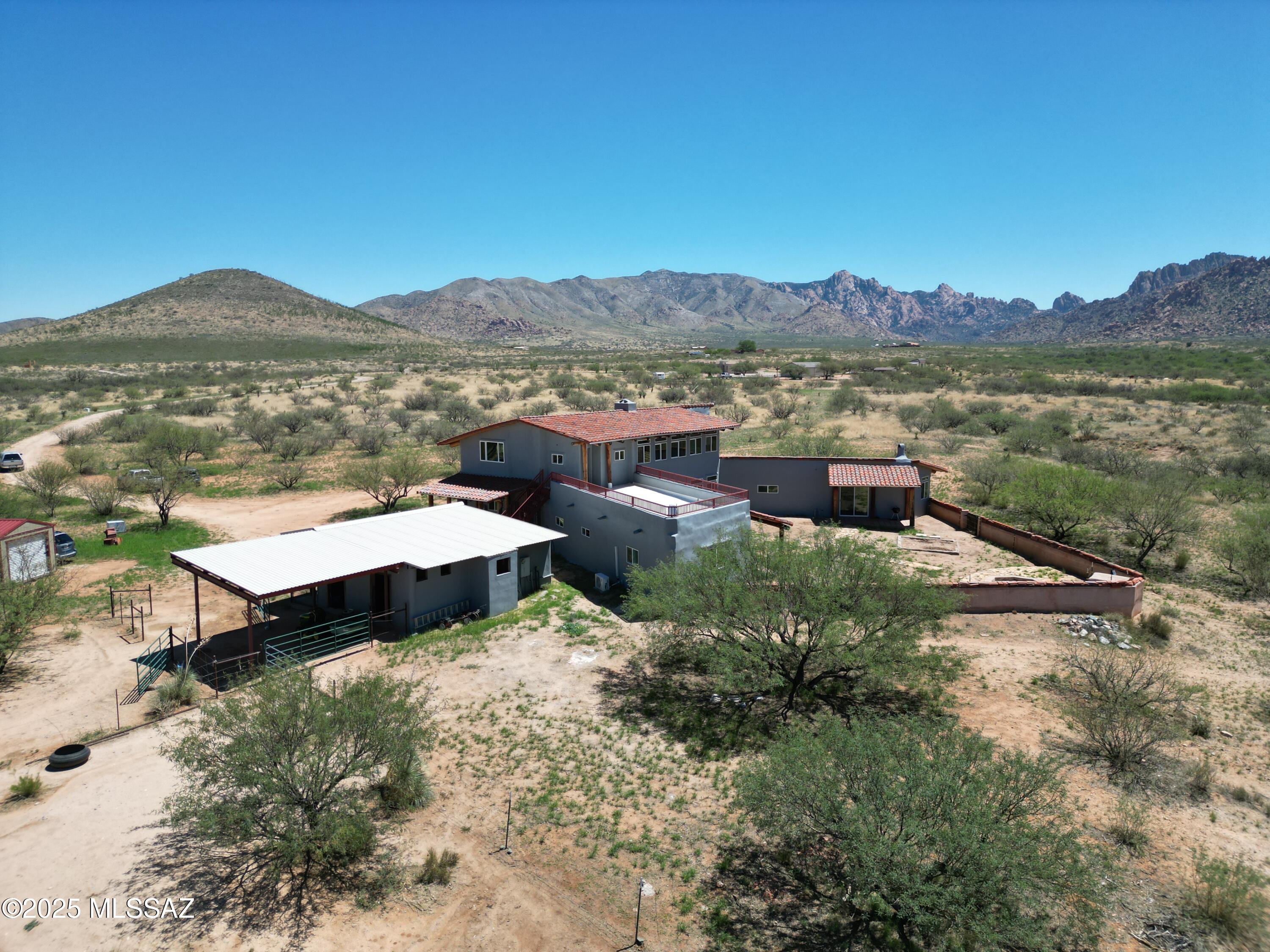 Nestled in the foothills of the majestic Dragoon Mountains in southeast AZ this spectacular custom estate spans over 39 acres of high desert land, offering a blend of luxury and natural beauty. Embrace a lifestyle of serenity and elegance, all within the safety of a gated community and the added benefit of HOA property value protection. With 4,180 square feet of living space, this 4 bedroom 2 bath home showcases high ceilings and the rustic charm of natural log beams. The great room features a striking fireplace.  This house boasts two primary bedrooms, each with its own fireplace. Enjoy peaceful nights and tranquil mornings in your private retreat, where comfort meets elegance. Bring your horses, facilities on site. 2nd level unfinished apartment with outside stairs.