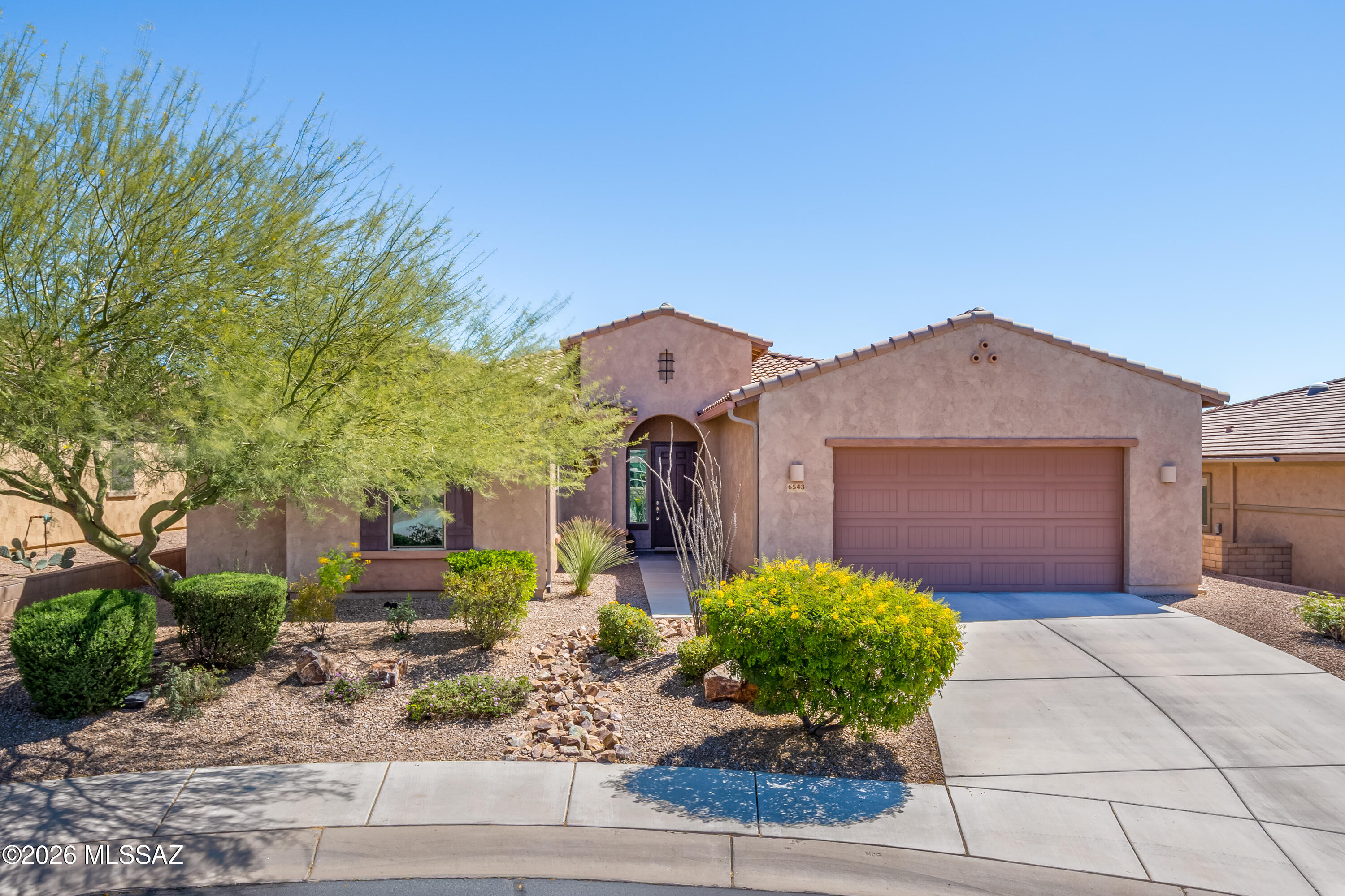 Enjoy spectacular sunrise views over the golf course from this beautifully designed home located in the desirable Los Saguaros community of Dove Mountain.
This spacious residence features 3 bedrooms plus a dedicated office/den and a 3-car tandem garage, offering both flexibility and functionality. The thoughtfully designed open floor plan showcases tile flooring throughout the main living areas with comfortable carpet in the bedrooms, creating both durability and warmth where it matters most.
The well-appointed kitchen is perfect for everyday living and entertaining, featuring double ovens, a cooktop, a natural stone island, and abundant cabinetry with soft-close doors and drawers, along with glass-front cabinet accents. The layout provides generous prep and storage space while remaining open to the living and dining areas.
Both bathrooms offer dual sink vanities, providing comfort and convenience, while the home also includes a mud room and a separate laundry room designed to keep daily life organized.
Step outside to enjoy the covered back patio overlooking the golf course, ideal for relaxing mornings and entertaining evenings. The backyard is designed for Arizona living with a spool (spa/pool combination) and a built-in outdoor grill, creating the perfect setting to enjoy the beautiful desert surroundings.
Located in the Los Saguaros neighborhood within Dove Mountain, this home offers a great floor plan, scenic golf course setting, and exceptional indoor-outdoor living in one of Southern Arizona's most sought-after communities.