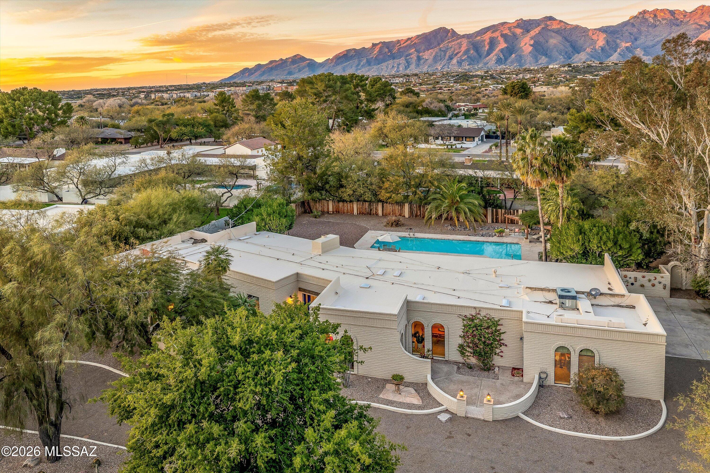 Stunning territorial ranch in the coveted, gated Tucson Country Club Estates. Spanning nearly 4,000 sq. ft., this home offers four bedrooms and four remodeled bathrooms, generous living spaces, and an updated kitchen with stainless appliances and a high-end gas range. Arched windows and skylights fill the interiors with natural light, while high ceilings, exposed wood beams, and exposed brick add timeless midcentury character. Multiple living areas include a family room with gas fireplace, two living rooms, and formal dining room. Luxurious primary suite with seating area and patio access. Two-car garage with ample storage. Resort-style backyard features a covered patio, heated pool, pergola, and Catalina Mountain views-perfect for entertaining or relaxing in your private Tucson oasis!