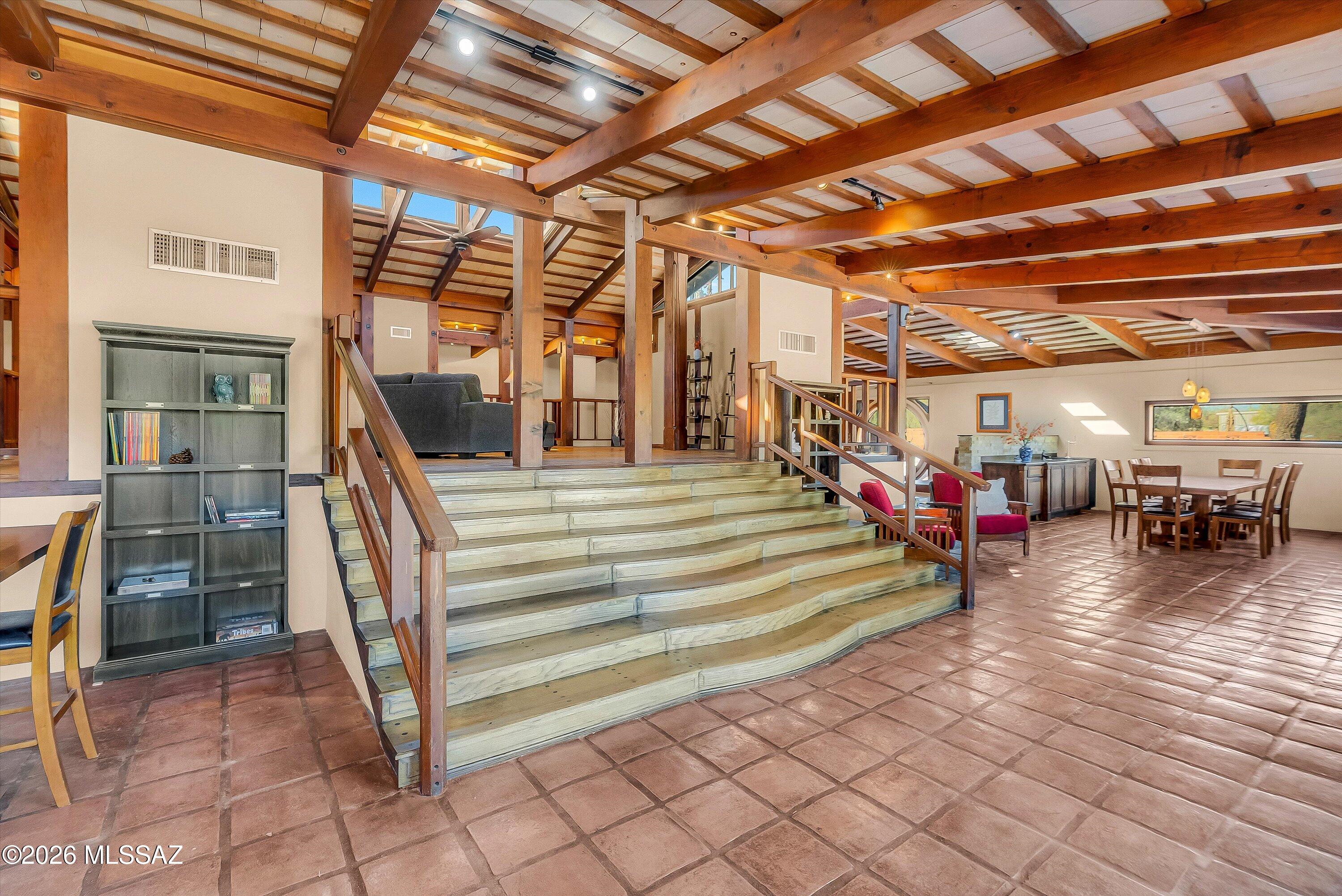 A home with a personality all its own. In Harold Bell Wright Estates, this distinctive residence pairs the warmth of a mountain lodge with bold architectural details and Catalina Mountain views. A raised central pavilion welcomes daylight through upper windows, while two striking six-foot circular windows give the home its signature character--one framing the Catalinas. Hand-carved woodwork, oak and pine flooring, and Saltillo tile bring warmth and texture to the open living areas. The approximately 4,080-square-foot home offers four bedrooms and 3.5 baths, including two primary suites. Both guest bedrooms have their own exterior entrances, adding flexibility to the layout. Cherry cabinetry, stainless steel appliances, and a generous island complete the kitchen. Set on approximately two-thirds of an acre with solar, RV parking, and no HOA, the property combines distinctive architecture with everyday convenience near east Tucson shopping, dining, and golf. Come experience the light, craftsmanship, and character in person.