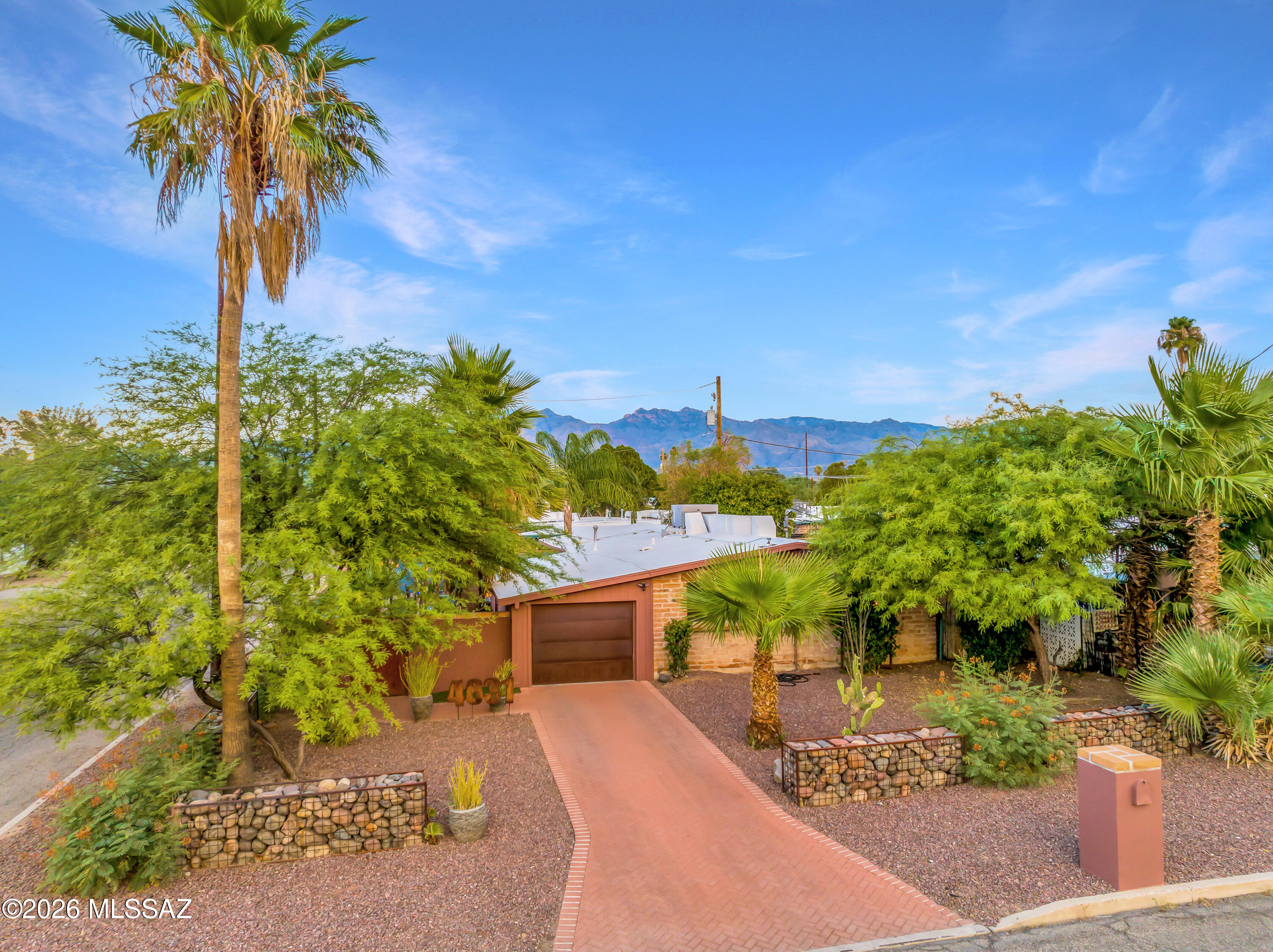 Set in a sought-after Midtown location with rare walkability to shops, coffee, dining & transit, this thoughtfully maintained home offers an easy, connected Tucson lifestyle. The private, fully walled & gated backyard is a true retreat--lush, low-care landscaping, mountain views, synthetic turf & a striking fire pit create the perfect setting for everyday living or entertaining. A spacious shed adds flexibility as a studio or workspace.  Inside, high ceilings & a light, open feel pair with a functional layout & attached garage & laundry for comfort and convenience. Just 3.5 miles to the University of Arizona, the home has also proven its value as a successful short- and mid-term rental, offering optional income potential. No HOA with room to personalize, expand or explore ADU options. Balinese statues are beautiful and unique wood carvings, however, if buyer prefers to enjoy the lush oasis-like garden without them, the seller can remove them!  Truly a one of a kind place!!