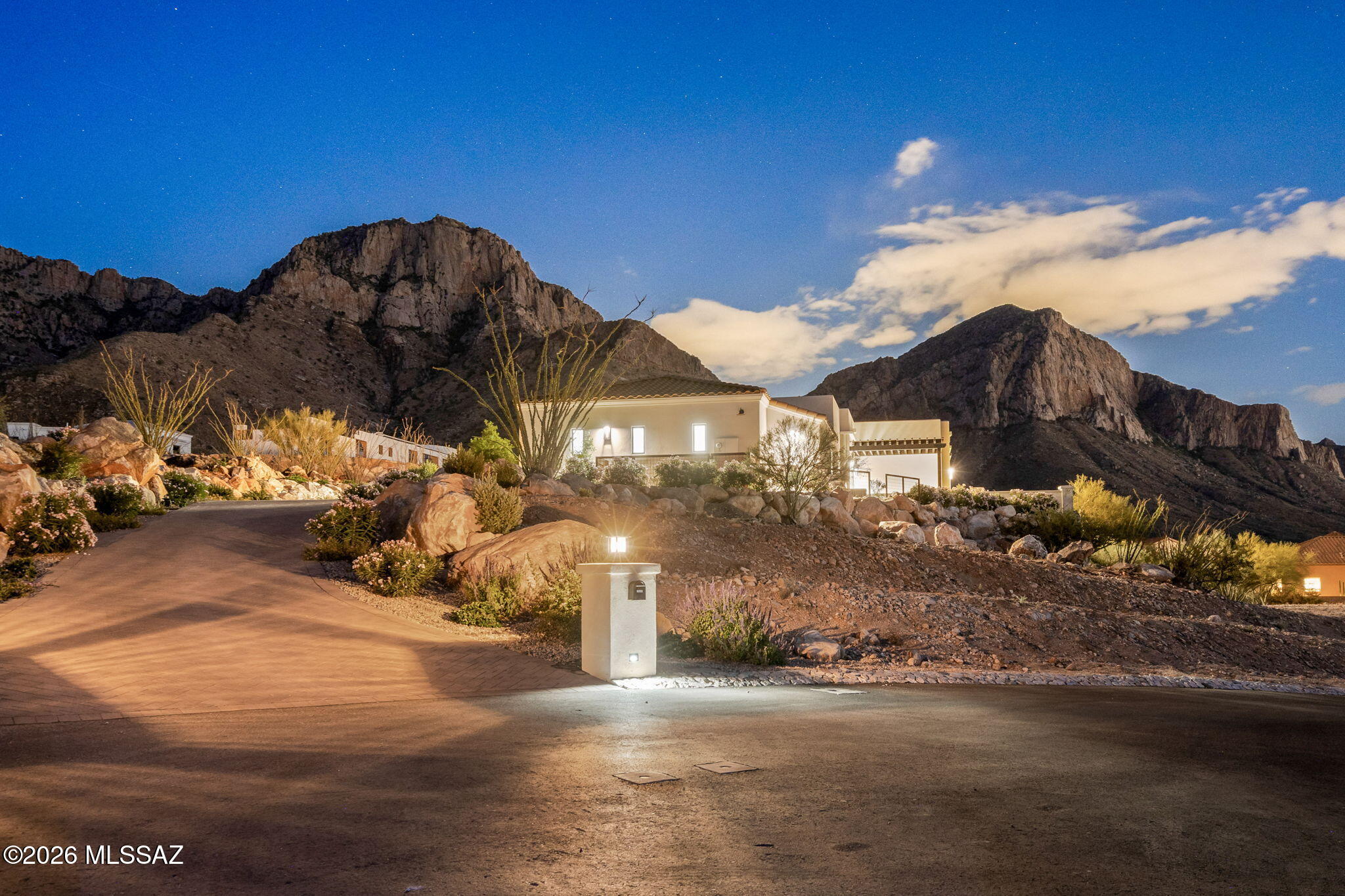 Breathtaking panoramic mountain views and city views. An open-concept floor plan with seamless flow between the Kitchen, Living Room, and Dining areas. Chef's kitchen, with elite Thermador appliances, an eleven-foot island, Taj Mahal quartzite countertops, custom cabinetry, and separate built-in coffee and cocktail bars. The adjoining living room serves as the centerpiece of the home, complete with a dual-burning fireplace, Brookfield glass doors, custom built-in shelving, and cabinetry. Primary suite occupies the south wing of the residence, creating a true retreat separate from the guest accommodations. The luxurious primary bath features separate his-and-her cabinetry, dual private water closets, and a custom-designed walk-in closet with extensive built-in storage. Two generously sized guest suites occupy the north wing of the home, each offering a full bathroom, a walk-in closet, a private patio, and unobstructed mountain or sunset views. 
The oversized garage is equally impressive, featuring professionally installed polyaspartic flooring, dual split air-conditioning systems, and a dedicated full bath that provides added convenience for outdoor activities, projects, or use in the garage gym.
This is a rare opportunity to own a meticulously designed desert luxury residence where elevated craftsmanship, sophisticated finishes, and unforgettable panoramic views converge in perfect harmony.