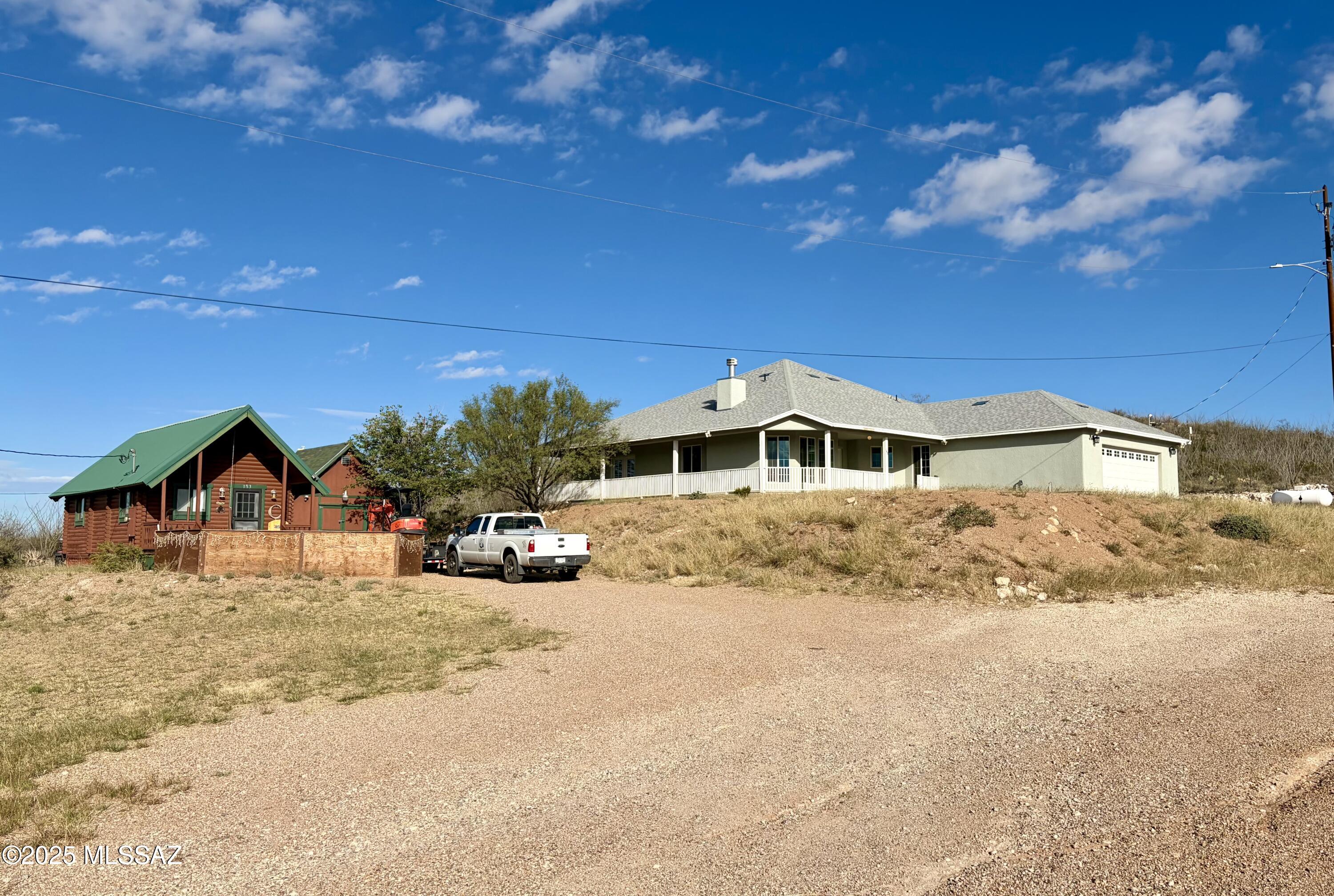 Perched high above historic Tombstone, this half-acre hilltop hideout offers panoramic 360° views. Built in 2019, the 2,180 sq ft main home features 2 beds, 2 baths, granite counters, high ceilings, dual-pane windows, a cozy fireplace, and a surround-covered porch—perfect for quiet sunset reflections. The oversized garage is ready for hobbies or projects. An additional outbuilding is perfect for gear and storage. The 394 sq ft guest cabin or bunkhouse adds 1 bed and 1 bath, ideal for company, outlaws and cowpokes passing through the Old West. Total 2,574 sq ft.  Take a short 5 minute amble on down to the boardwalks and visit towns folk, shops, stage line and saloons of the legendary world-famous and historic streets of Tombstone!