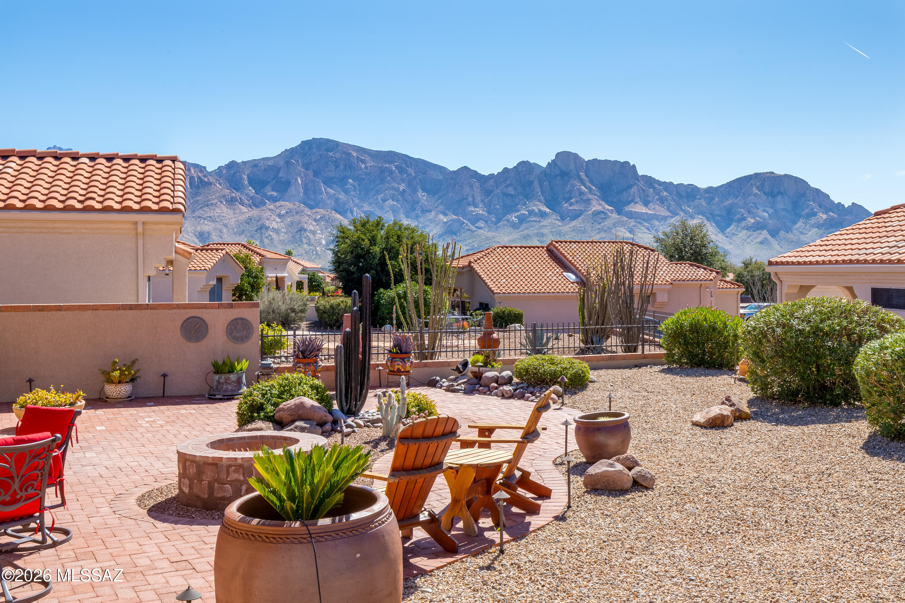 Charming 1,093sf 2BR/2BA Oasis floorplan in Sun City Oro Valley, situated on a fully fenced lot w/stunning mountain views. Inviting fully-fenced front courtyard features pavers. Paver driveway adds to the curb appeal. Kitchen has newer maple cabinets w/pull-outs, quartz countertops & stainless-steel appliances. Bay window in breakfast nook has beautiful mountain views creating the perfect setting for morning coffee. Wood flooring extends through most of the home with ceramic tile in the kitchen & guest bath. Updated interior doors & baseboards add a fresh, modern touch. 2nd bedroom features a built-in desk & sliding glass door to patio ideal for guests or home office. Both bathrooms have been tastefully updated. Covered patio has ceiling fan & remote-controlled sunscreens. Additional upgrades include newer roof (2017) w/gutters & Leaf Guard. Newer HVAC (2022). Extended brick walkway & firepit in the fully fenced backyard. Spacious side yard too! Garage has storage cabinets & epoxy-coated floor. This home is a true gem in a spectacular location! Enjoy all that Sun City Oro Valley has to offer, including an award-winning championship 18-hole golf course, tennis, pickleball, restaurant, expansive recreation centers, over 130 clubs and activities, and exceptional amenities designed for an active lifestyle. Conveniently located near medical facilities & Oro Valley Marketplace with shopping, dining & movie theater.
