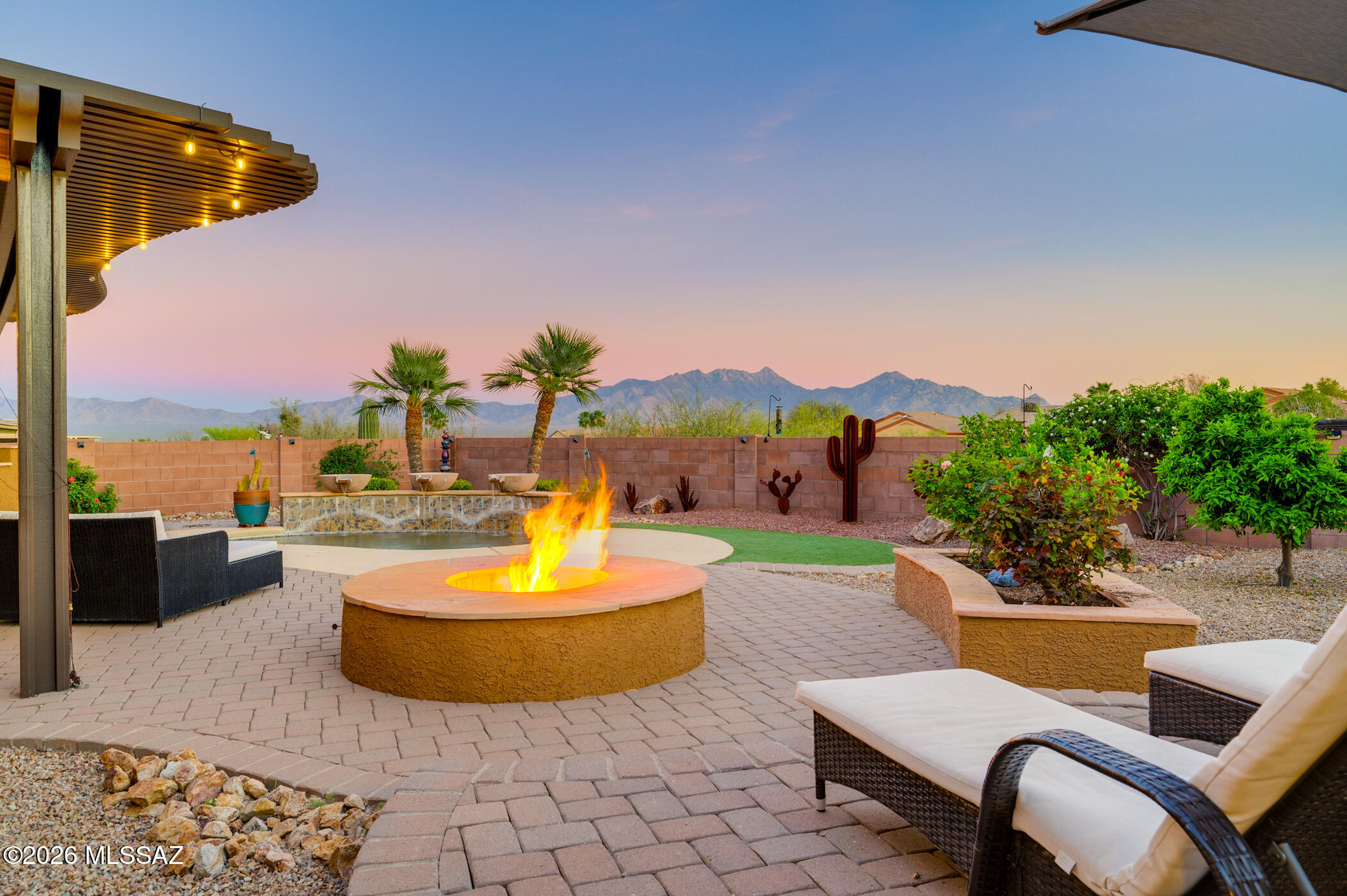 Discover the epitome of retirement elegance nestled in the serene ambiance of Green Valley, AZ.  This exceptional residence is a secluded retreat, featuring stunning mountain vistas and access to peaceful walking trails that promote an active lifestyle. Step into a world of sophistication with striking curb appeal, accentuated by a charming front paver courtyard, complete with a tranquil fountain that welcomes you to a life of luxury.  Upon entering, one is welcomed into a space defined by 10-foot ceilings and expansive windows that let abundant natural light permeate throughout, creating an atmosphere that is both spacious and inviting. Every element of the home has been meticulously crafted for comfort and style, from the attractive neutral-tone tile flooring that offers endless decorating possibilities to the dream kitchen outfitted with exquisite cabinetry, granite countertops, and high-end appliances, including a gas cooktop, double wall oven, and microwave. The great room, anchored by a cozy corner fireplace, serves as an ideal setting for social gatherings while preparing impressive culinary creations. The primary suite is a sanctuary of relaxation, featuring a generously sized layout with ample space for additional seating and an ensuite bathroom complete with a corner soaking tub, a separate shower, and a dual-sink vanity. Accommodate guests effortlessly with a designated guest room and a versatile hobby room that could serve as a third bedroom.  Double French doors lead to a sophisticated den or office space, complete with plantation shutters for added elegance. Outdoor living is redefined with a spectacular private yard adjacent to a natural desert arroyo. An aluminum ramada extends your living space, while the outdoor kitchen and gas firepit create an enchanting environment for evening gatherings. The spool, equipped with a commercial-grade heater, ensures year-round enjoyment. Beautiful landscaping, including mature grapefruit, lemon, orange, and apricot trees, is maintained by the newly installed irrigation system. The extended garage provides overhead storage, enhancing the home's practicality. Sunrise, sunsets and amazing stars overhead - this home transcends mere living space--it's a lifestyle for those who appreciate privacy, beauty, and the finer things in life.