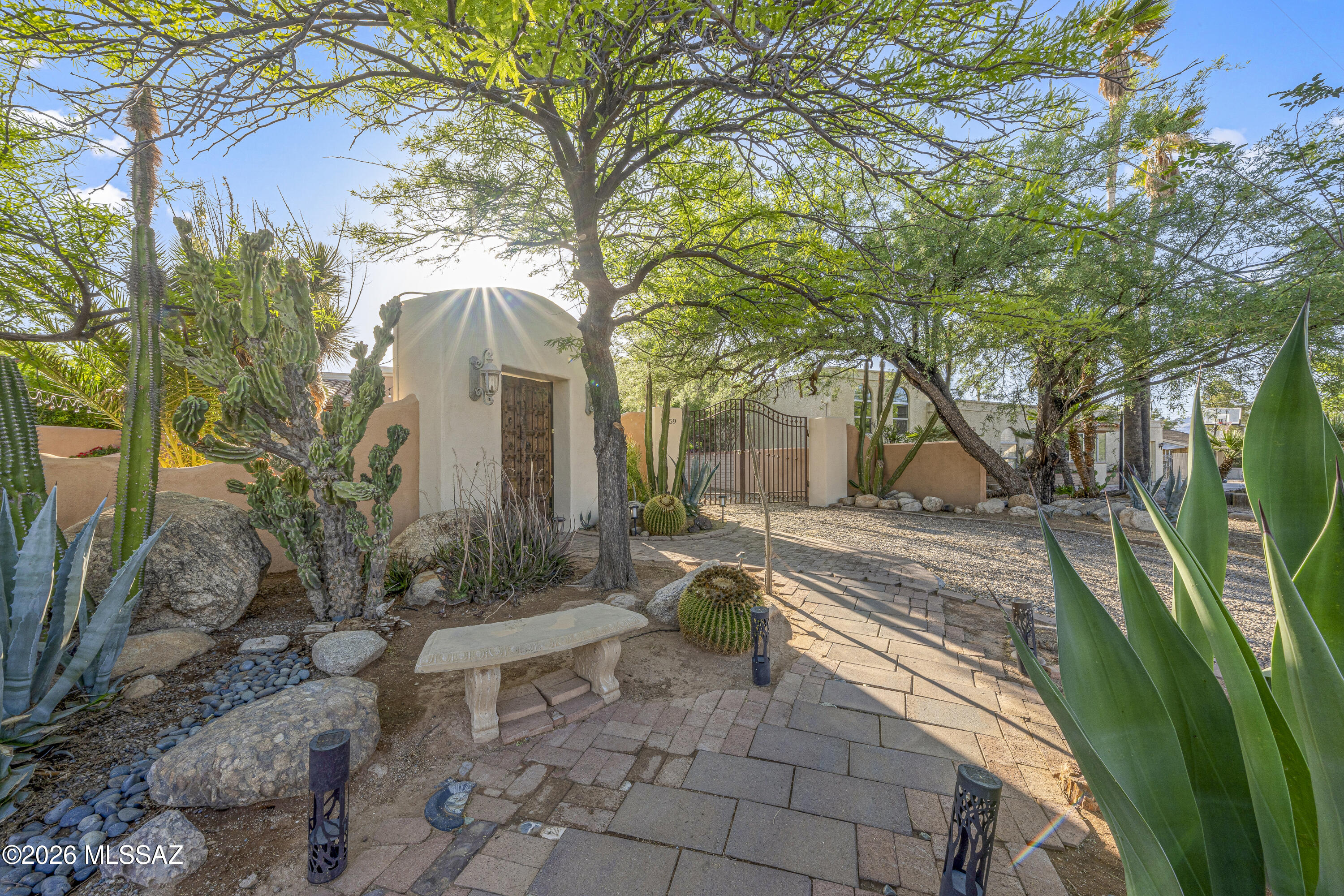 Charming Santa Fe-style retreat with gated courtyards and inviting outdoor living. 2BD/1BA featuring travertine floors, carpeted bedrooms, and fresh interior paint. Functional layout includes a separate laundry room and detached storage.

Enjoy a beautiful front patio with Carrera stone fountain and beehive fireplace--perfect for relaxing or entertaining. One side yard offers mature citrus trees, while the other provides space for gardening, plus a greenhouse for year-round growing. There is a large Studio/storage room with North Light.  Large gated driveway big enough for a large truck and sedan. South yard side gate big enough for an RV.

Private, character-rich, and thoughtfully maintained--Southwest living with style at an approachable price.  Owner agent.