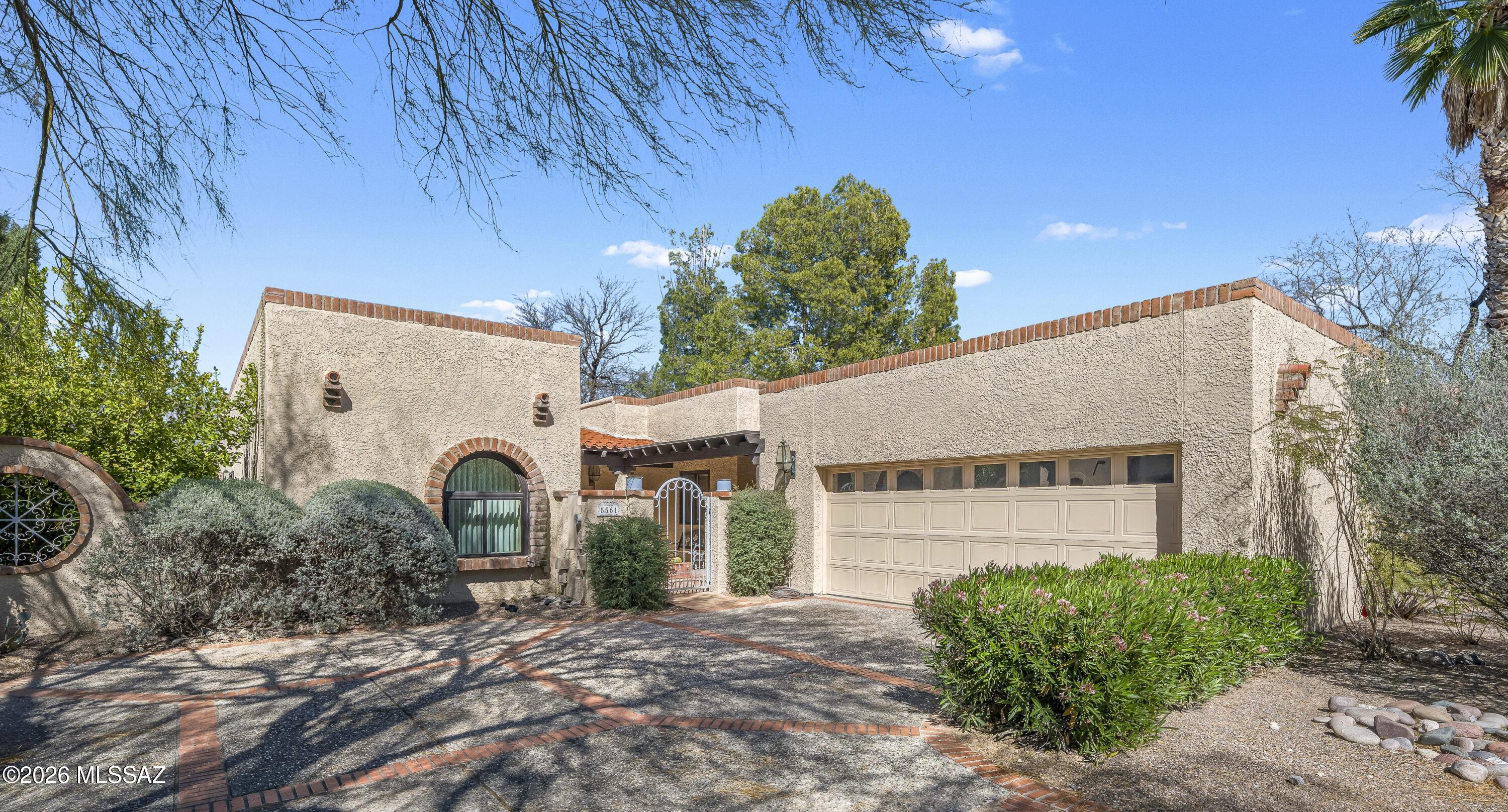 Located in the coveted gated San Miguel community, this 2,566 SF  free-standing patio home offers timeless Southwestern character & old world charm. Courtyard entry & double doors lead to the dramatic foyer that welcomes you into the home, where vaulted wood beam ceilings, classic Saltillo tile & colorful Talavera accents create warmth & architectural interest throughout. Spacious kitchen features double ovens, cooktop & sunny breakfast nook, while a wetbar & cozy fireplace in the living room add charm & functionality. Large primary w/WI shower & soaking tub. Enjoy outdoor lifestyle on the side patio or the north-facing backyard. Resort-style amenities including a pool, spa, tennis/pickleball court, & clubhouse. Excellent location near Ft. Lowell Park, The Loop, Whole Foods & more.