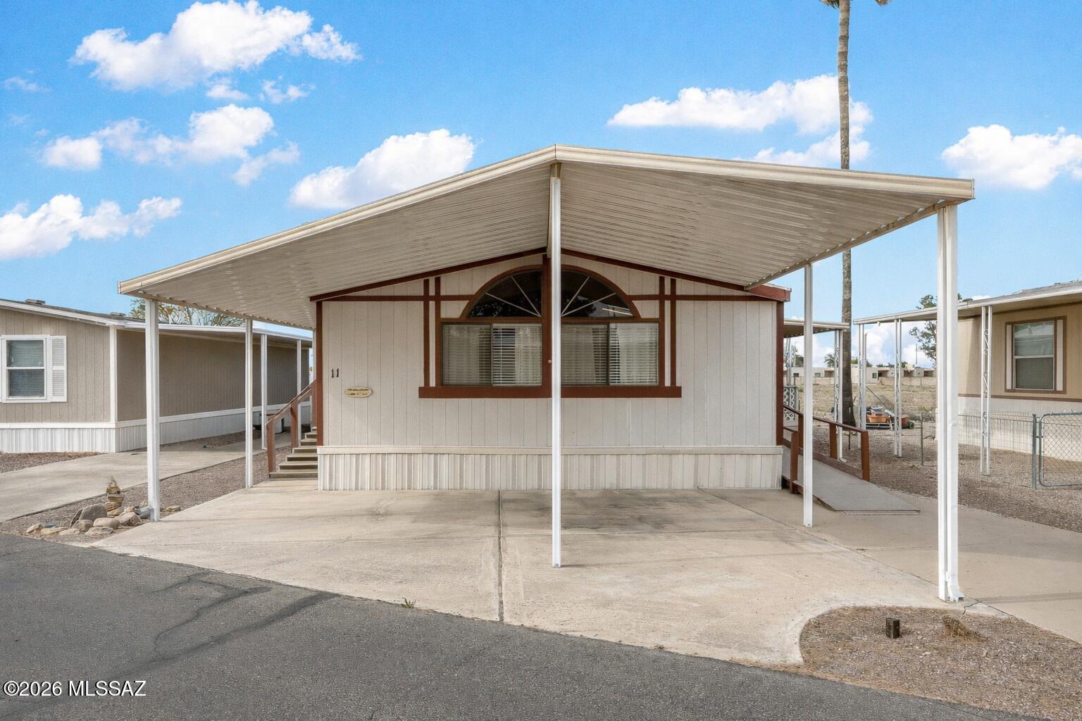 Welcome to this well-maintained 2-bedroom, 2-bath home in the desirable 55+ Valley of the Sun Mobile Home Park. Offering approximately 1,450 sq. ft., this home features a bright living room with arched windows, a spacious dining area, and a functional kitchen with ample cabinet and counter space. The primary suite includes a private bath, while the second bedroom is perfect for guests or a home office. Enjoy the convenience of an indoor laundry room, covered patio, fenced yard, and covered two-car carport. Located just steps from the community pool, recreation center, and mailboxes, this home offers comfort, convenience, and an active Arizona lifestyle. Land lease is $634/month.