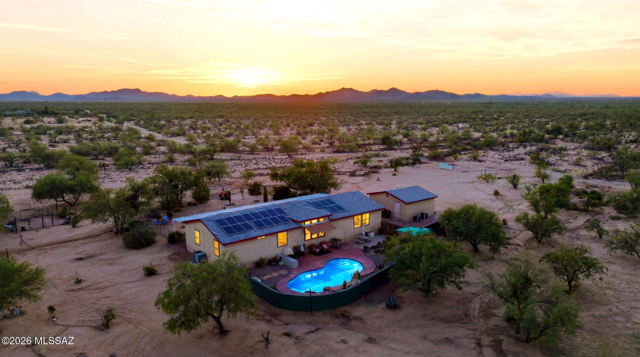 Experience the perfect blend of sustainability, space, and luxury with this exceptional 5.72-acre estate. Designed for ultimate energy efficiency, this property features fully owned and completely paid-off solar panels, resulting in an incredible average electric bill of just $20 a month. Fully fenced for maximum privacy and security, the expansive acreage offers endless possibilities and includes a spacious detached garage perfect for vehicles, workshop space, or recreational toys. Inside, the home is masterfully laid out with 3 bedrooms, 3 bathrooms, and two separate living rooms that provide abundant space for both entertainment and relaxation. The massive kitchen is a chef's delight, equipped with sleek stainless steel appliances and ample space for storage provided by beautiful cabinetry. Laundry room is complete with an efficient washer-dryer combo unit, granting more space for storage and organization. Speaking of storage, it is never an issue, as every single bedroom boasts its own walk-in closet. The impressive layout features a junior suite with its own private attached bathroom and walk-in closet, while the main master suite offers a spa-like bathroom experience featuring a luxurious jetted tub and separate shower. Step into the backyard to discover a professionally landscaped desert oasis designed for outdoor living. Cool off in the sparkling in-ground pool, unwind on the patio sipping your beverage of choice, and take in panoramic Arizona sunsets that paint the sky every evening. With nearly six acres of private land, energy-independent living, and resort-style amenities, this property is a rare find that delivers total comfort and peace of mind.