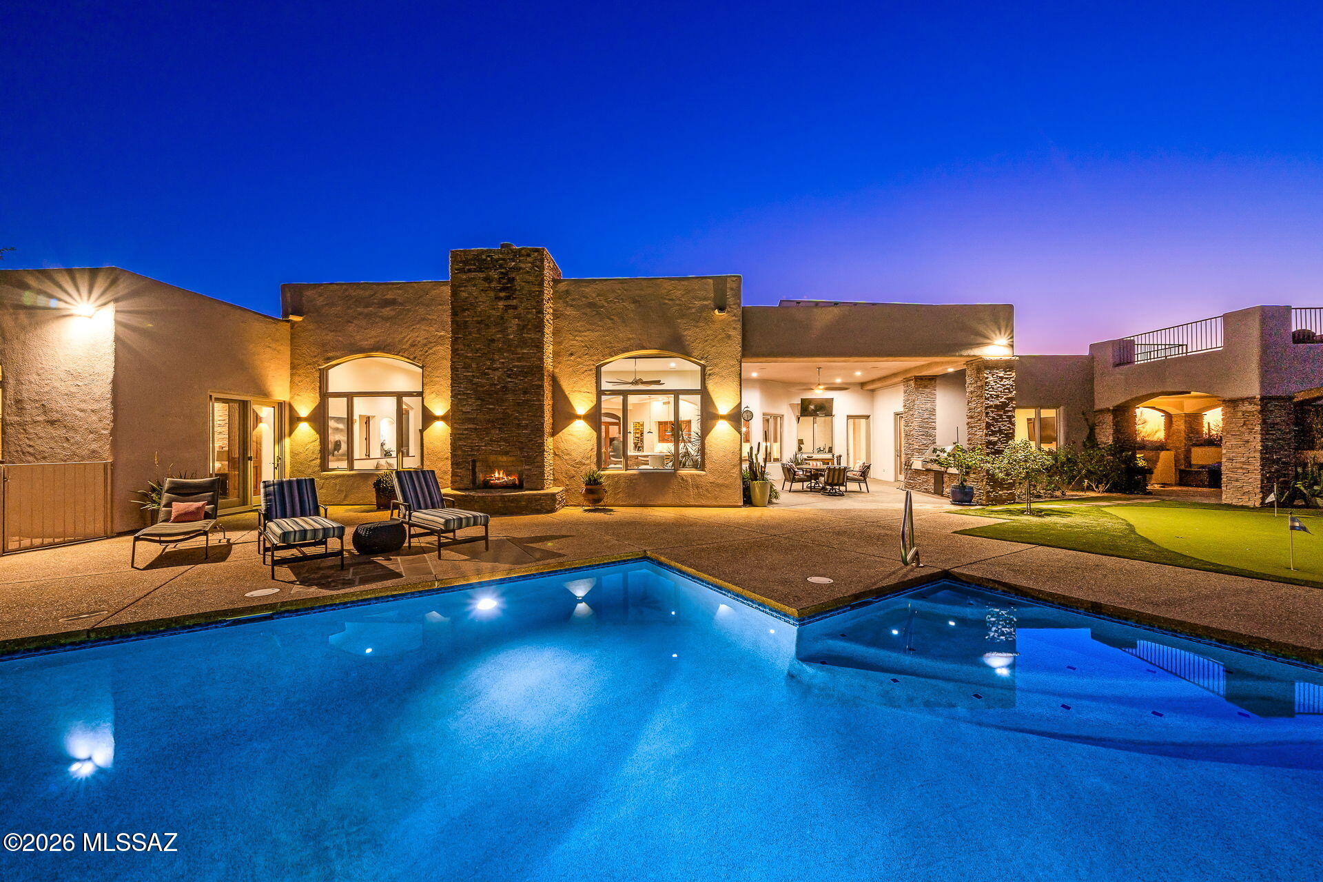 Perched high above the city within the prestigious 24/7 guard-gated community of Pima Canyon Estates, Framed by the Santa Catalina Mountains and Tucson's legendary dark skies, this architecturally distinctive desert retreat blends timeless masonry, privacy, and effortless indoor-outdoor living. Arrival is quietly dramatic, beginning with a discreet motor court, porte-cochere, exposed concrete walkways, and a custom steel-and-glass entry anchored in stacked stone. Inside, the desert does not disappear--it becomes the view. Soaring ceilings and walls of glass draw the Catalinas into everyday living, while travertine floors flow through an open plan designed for both relaxed living and effortless entertaining. Thoughtful North/South orientation, a whole-house water filtration system, reverse osmosis, Sonos, three Rheem/Ruud 14-SEER HVAC units replaced between 2021 and 2023 with upgraded 4-inch filtration, and privately owned solar panels deliver exceptional comfort and efficiency, with an average electric bill of approximately $35 per month. A 930-square-foot three-car garage includes an EV charging station.

At the heart of the home, the kitchen serves as a natural gathering space, appointed with Mont Blanc quartzite countertops, a seamless integrated backsplash, custom cabinetry, high-end appliances, and Visual Comfort lighting. French doors open to a veranda courtyard, where city lights and mountain silhouettes create an unforgettable backdrop for sunset dinners and evening conversation.

The private single-level primary wing is positioned for sweeping Catalina views and complete privacy, and includes an electric fireplace along with an adjoining meditation or bonus room. The spa-inspired bath offers dual vanities, a generous walk-in shower, and a freestanding soaking tub designed for true retreat.

On the opposite side of the home, two additional bedrooms feature renovated en-suite baths and share a private living area, ideal for guests or multigenerational living. A substantial fourth bedroom is perfectly suited for a dedicated home office.

Outdoors, the architecture continues with a pool replastered in 2021, along with a replaced gas heater, LED pool light, and Pentair ScreenLogic control system. An elevated spa, putting green, and spiral staircase leading to a private view deck create a true desert retreat--your front-row seat to Tucson's color-washed sunsets and star-filled nights. A separate veranda with a trickling fountain offers yet another quiet, restorative corner of the grounds.

More than a home with views, this is a sustainable, secure, and refined desert retreat built around privacy, architectural character, and the very best of Sonoran Desert living.