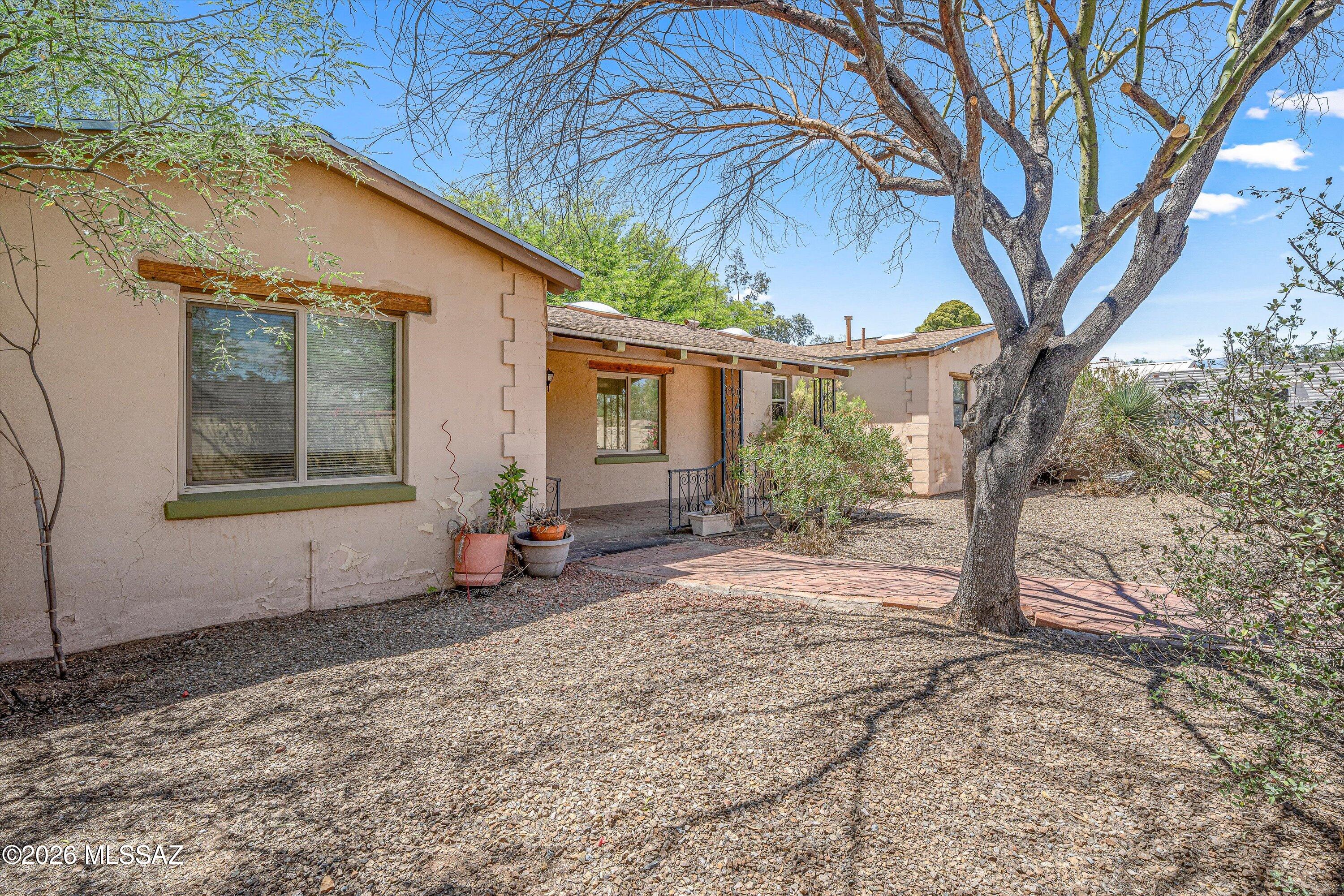 Built in 1941, this 4-bedroom, 2-bath home reflects the character and charm that define Tucson's historic neighborhoods. Nestled beneath mature shade trees on a 0.34-acre lot in the heart of Central Tucson, the property offers a pool, no HOA, and a location that's hard to beat. A circular driveway, gated courtyard, and welcoming front porch create a memorable first impression, while the spacious lot provides room to relax, entertain, and enjoy Tucson's outdoor lifestyle. 
At the center of the home, the kitchen combines functionality and character with abundant cabinetry, granite countertops, pendant and recessed lighting, black appliances, and an electric range. The adjoining dining area creates an easy flow for meals, gatherings, and everyday living.
The spacious living room showcases a a wood-burning fireplace, custom built-in shelving, skylights, and abundant natural light. The thoughtfully designed floor plan offers comfortable gathering spaces while maintaining privacy between the primary suite and secondary bedrooms. 
The private primary suite features a large walk-in closet and an updated ensuite bath with a beautifully tiled walk-in shower. Three additional bedrooms provide flexibility for guests, hobbies, workspace, or other needs. A separate laundry room adds everyday convenience. 
Step outside to enjoy the oversized backyard, complete with a pool, covered patio, mature landscaping, and plenty of room to relax, entertain, garden, or simply enjoy Tucson's beautiful weather. A detached garage and storage shed provide additional storage and workspace options, while the 0.34-acre lot offers room to spread out in the heart of Central Tucson. 
Located in the desirable Broadway Village area, you'll enjoy convenient access to the historic Broadway Village Shopping Center, locally owned restaurants, coffee shops, parks, the University of Arizona, Banner University Medical Center, and downtown Tucson. Rooted in Tucson's rich history, the area is known for its distinctive architecture, mature trees, and central location, offering a blend of character and convenience that is uniquely Tucson.