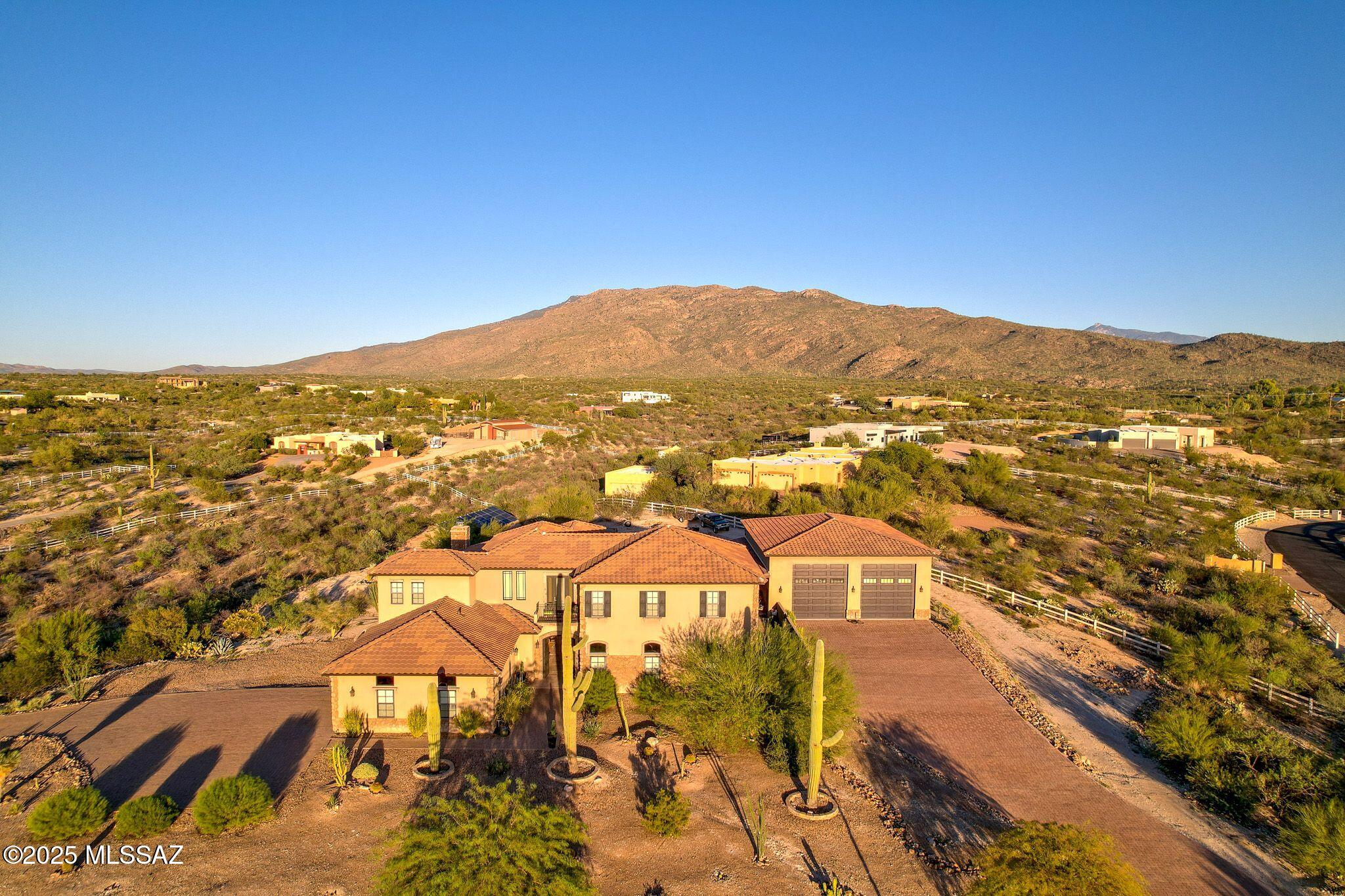 A Tucson Masterpiece: Hilltop Luxury with Unrivaled Views

Perched majestically on 3.3 acres in the gated community overlooking the Sonoran Desert, this hilltop estate is a rare Southern Arizona jewel, offering over 5,000 sq ft of sophisticated living space and 360° panoramic vistas of the Catalina and Rincon Mountains, Tucson city lights, and the protected lands of Saguaro National Monument East. Every sunrise and sunset becomes a private spectacle in this serene desert sanctuary.

Crafted with steel-frame construction and powered by an owned solar system, the home blends modern sustainability with timeless Southwestern strength. Two stories plus a fully finished basement including a full bathroom and storage room are seamlessly connected by a custom wrought-iron staircase with stone and mesquite inlaid steps, ascends to the dramatic focal point: the most majestic circular chandelier you'll ever see, illuminating the heart of this exceptional estate.

The gourmet kitchen is a chef's dream, featuring custom cabinetry, granite countertops, high-end appliances and a huge granite island perfect for entertaining. A secondary butler's kitchen includes a double oven, farm sink, and oversized refrigerator/freezer, offering both functionality and elegance for large gatherings.

The living area showcases breathtaking views and a custom stacked stone fireplace, creating a cozy and dramatic focal point for cool desert nights and intimate gatherings.

The Primary suite, occupying the entire second floor, is a sky-loft retreat with sweeping views in every direction. It features his-and-her offices and a spa-inspired Primary bathroom with a custom stone soaking tub, walk-in granite rainfall shower, and spacious walk-in closet. A full-length private balcony stretches across the entire suite, offering unparalleled views of the Rincon Mountainsthe perfect place to enjoy morning coffee or evening sunsets.

The Guest suite, nestled under the master and connected via a charming breezeway, is a private oasis. Complete with a fireplace, luxurious soaking tub, walk-in shower, and walk-in closet, it provides comfort and privacy for family or guests. With double doors leading outside, it's just steps away from the pool area.

For the automotive enthusiast, the estate offers a 2-car attached garage, also, an enormous detached 8-car garage equipped with a car lift, a workshop, it's heated and cooled, a loft for extra storage or possibly another office space, 2 large garage doors in front and another in back for pull through capability. The detached garage also includes a workout room with a full bathroom and shower, providing convenient access for anyone enjoying the pool or the outdoor spaces.

Step outside to your private desert resort: a sparkling pool with waterfall and resistance-current system, perfect for leisurely swims, fitness, or enjoying warm Arizona evenings under the stars. A state-of-the-art outdoor projector TV lets you watch your favorite team or movie from the pool, creating the ultimate desert entertainment experience. Entertaining, relaxing, and desert living all converge here in perfect harmony.

This estate is a rare fusion of architectural artistry, luxurious amenities, and the unmatched natural magic of Southern Arizona. With its grandeur, privacy, and breathtaking setting, it stands as one of Tucson's most exceptional hilltop residencesan estate that must be experienced to be fully appreciated.