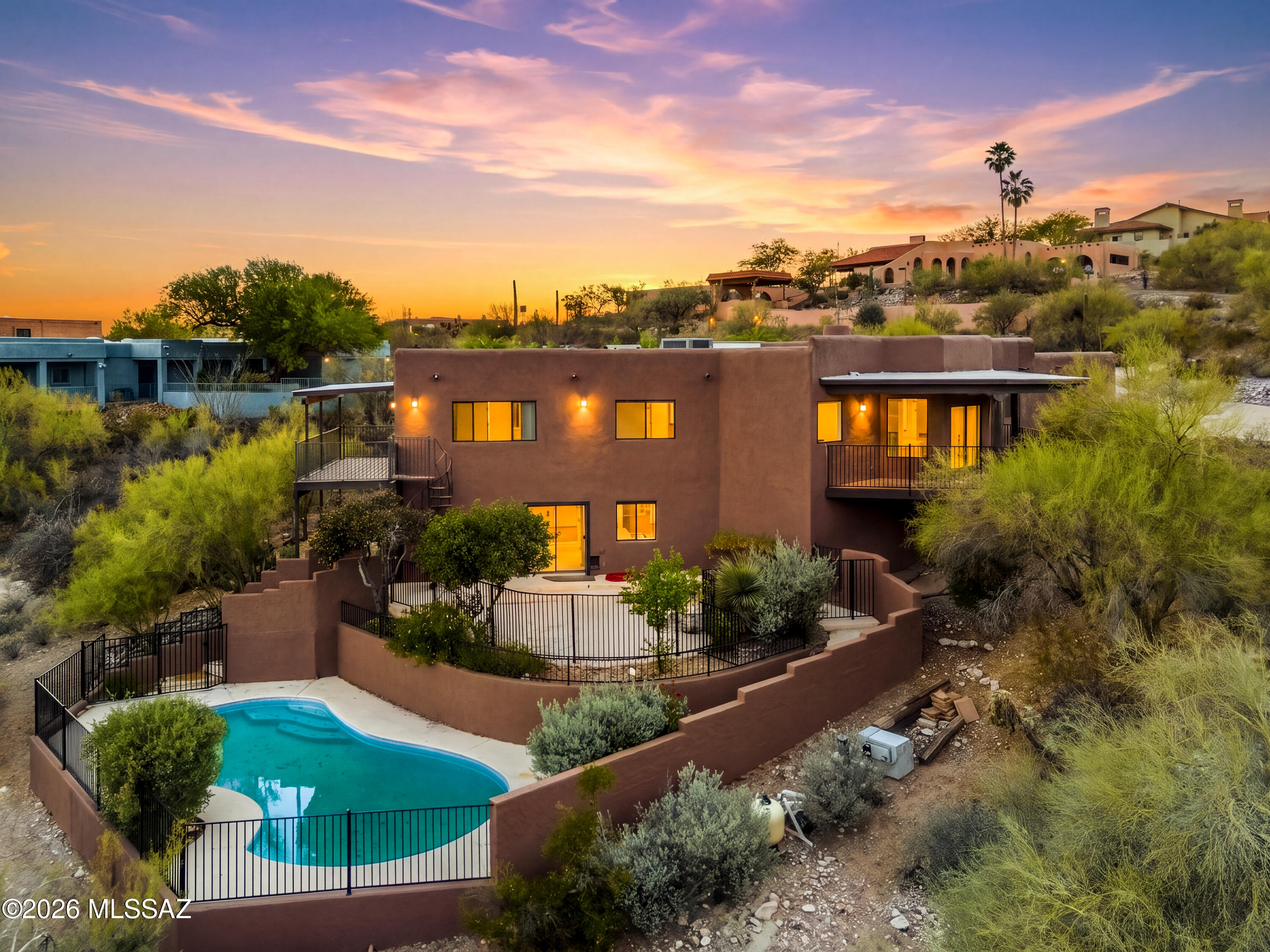 Nestled into the Catalina Foothills on a .92-acre lot, this 4 bed, 4 bath split-level home offers stunning mountain and city views, natural desert surroundings, and flexible multi-generational living. The main level features the primary living area with 3 bedrooms, 2 bathrooms, fireplace, and access to 3 balconies capturing views across Tucson and the Catalinas. The lower level offers a fully functional 1,000 sq ft guest quarters with kitchen and full bath, plus an additional 840 sq ft bonus room with half bath ideal for a theater, game room, gym, yoga studio, or home office. Pool access from both levels creates seamless indoor/outdoor living.