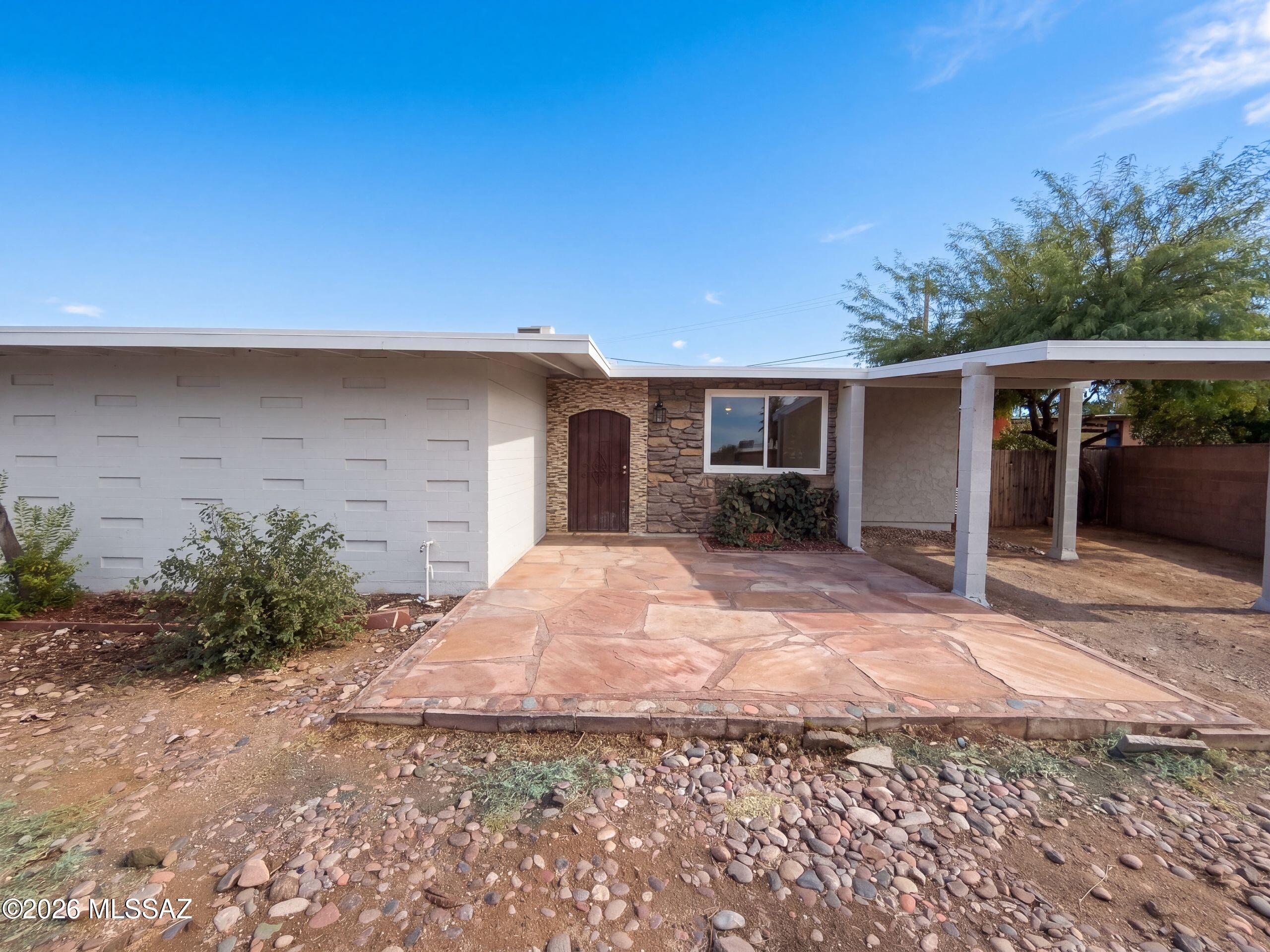 INCREDIBLE BUYER INCENTIVES: $3,000 MORTGAGE CONCESSION. Seller will pay up to $3,000 at closing towards your interest rate buydown if you finance with lender of sellers choice.

4252 E Sylvane Dr is a single-story Tucson home with a broad backyard, a rear patio, and distinctive stone accents inside and out. A substantial wood entry door with dark metal detailing opens into the living room, where a stone accent wall adds texture beside the seating area. A wide opening connects this room to the kitchen and dining space, with glass-paneled double doors and a transom framing the outlook to the backyard. The kitchen features white cabinetry, warm wood-look counters, and a gas range, with the patio directly beyond for outdoor meals. The bathroom includes a tub-shower combination with white ti