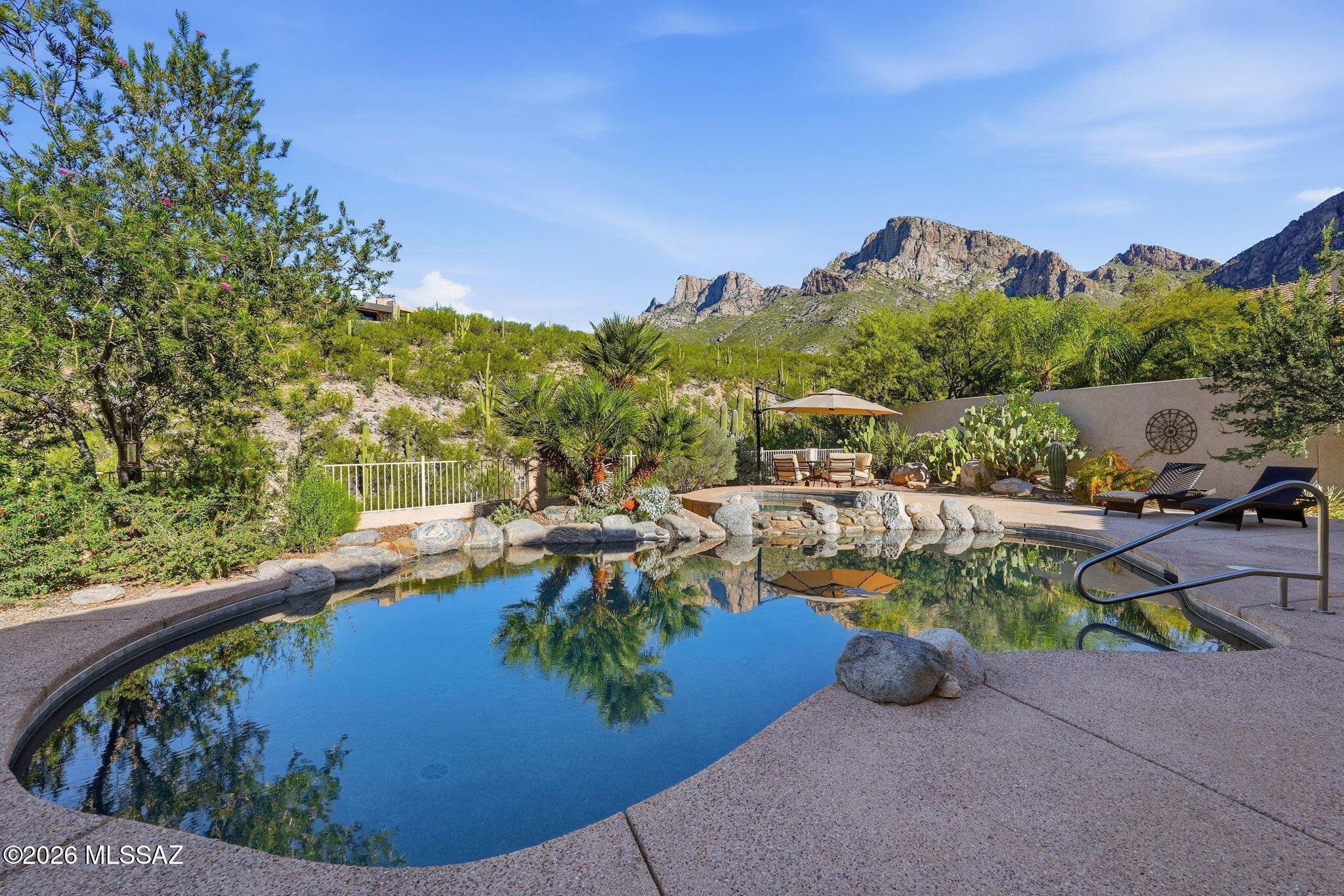 Perched on a premium elevated view lot in the desirable Bighorn Point enclave of guard-gated La Reserve, this beautifully updated and meticulously maintained home captures breathtaking, up-close views of Pusch Ridge along with sweeping vistas of the sparkling city lights beyond. Designed to embrace the best of Arizona living, the backyard is a true private oasis with lush landscaping, a PebbleTec pool and spa with a new energy-efficient WiFi-controlled heater, and a newly added brick-paver gathering area with gas fire pit--perfectly positioned to enjoy dramatic mountain views, colorful sunsets and twinkling city lights.
Inside, a spacious Great Room and desirable split-bedroom floor plan are enhanced by soaring ceilings, abundant natural light and thoughtful upgrades throughout. The inviting living space features a sleek, vented linear gas fireplace and wood shutters, while the kitchen offers cabinet pull-outs, a new induction range/oven and new refrigerator. The laundry room has been beautifully upgraded with new cabinetry and a butcher-block folding counter.
The primary suite includes a thermostatic shower temperature control, newly installed toilet and enhanced closet organization. The guest bath was completely refreshed in 2026 with new floor and shower tile, vanity, sink, toilet, shower valve and shower head, while the powder room features new flooring, vanity, sink and toilet. Custom hanging and shelving systems have also been added to the primary and both guest closets.
Outdoor comfort is enhanced by a power patio screen for sun and insect control and a removable power pool cover. Additional improvements include a 16-SEER main HVAC system, repaired window seals in 2026, and a versatile garage equipped with its own heating and cooling mini-split, eight wall-mounted storage cabinets, plus additional space ideal for a workshop or storage.
From morning light illuminating Pusch Ridge to spectacular sunsets and glittering city lights after dark, this exceptional home offers a rare combination of comfort, thoughtful upgrades and unforgettable views--all within one of Oro Valley's most distinctive guard-gated communities.