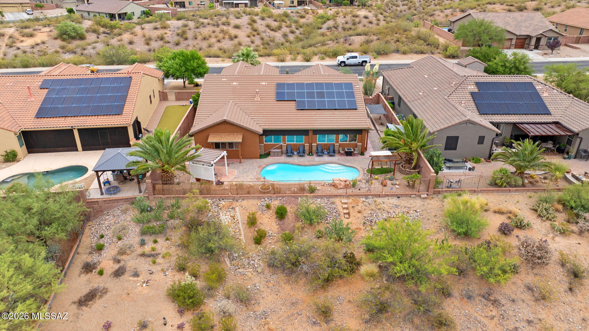 Amazing opportunity for updated 2,987 SqFt 3 bed/2.5 bath split floor plan with den and flex room, single story w/no stairs/no steps, 2009 built modern contemporary home on premium .22 acre elevated view lot featuring unobstructed panoramic Sonoran desert and Santa Rita mountain views, seller owned solar photovoltaic panels, heated pool, 633 SqFt attached 3 car finished garages located in the desirable gated community of Madera Highlands Encore. Featuring NE/SE orientation, mountain views, no neighbors in front or behind, modern flat concrete tile roof, concrete driveway, concrete sidewalks, freshly painted outside ($6500), on and off-street parking, landscaped manicured front yard w/crushed rock, Saguaro cactus, fruitless olive and palm trees, custom rustic garage doors, metal gutters, concrete walking path to secure gated enclosed front patio. Inside enjoy tall textured ceilings (no popcorn), energy efficient double pane windows, new custom matching blinds, solar window screens, luxury plank and tile flooring throughout (no carpet), built-in ceiling fire sprinkler suppression system, crisp white 8' internal doors, ADT alarm installed, zoned gas Trane HVAC system (new 2023 $27K),  dual digital Smart thermostats, Pex plumbing (no polybutene), plumbed whole home water filtration Green water softener & carbon filter system (new 2024 $3200), recessed lighting, luminated ceiling fans and formal dining area. Entertainer's dream open concept kitchen featuring full slab granite counter tops, matching massive full slab granite island with bar seating, self-closing designer staggered modern kitchen cabinets with lower cabinet pull-out shelves, stainless steel appliance package, convection oven, brick backsplash, butlers pantry with walk-in closet, laundry room with exhaust fan, washer and dryer included, adjacent to spacious great room with fantastic natural light, built-in 4 speaker surround sound and gas fireplace. Endless possibilities for the attached enclosed West facing tiled flex room, currently used as a home gym, with remote control outside electric powered shades. Large primary suite with full ensuite bathroom featuring dual walk-in closets, separate soaking tub, walk-in shower and matching dual executive height cultured marble modern vanities.
Attached 633 SqFt finished 3 car garage with remote controlled garage doors, concrete floors, provide ample room for workshop, toys, golf carts or convert a stall to home gym.
Epic Tucson sunsets await from your private backyard retreat with open wash and no neighbors behind, providing 180° unobstructed Santa Rita mountain views! Relax in your sparkling heated pool year-round, soothing waterfall, new electric pool heater ($3824 in 2023), cartridge pool filter, variable speed pool pump, raised flower beds, orange and lime trees, Tuff shed storage, Belgard brick pavers, plumbed for gas grills, ramada, side gates, view fencing surrounded by HOA approved raised privacy block walls. 
Affordable $117 monthly HOA includes secure gated entrance, community pool, basketball courts, tennis courts, grassy park, extensive paved walking paths, street and common area maintenance. Call to make your appointment to view this gorgeous move in ready home today!