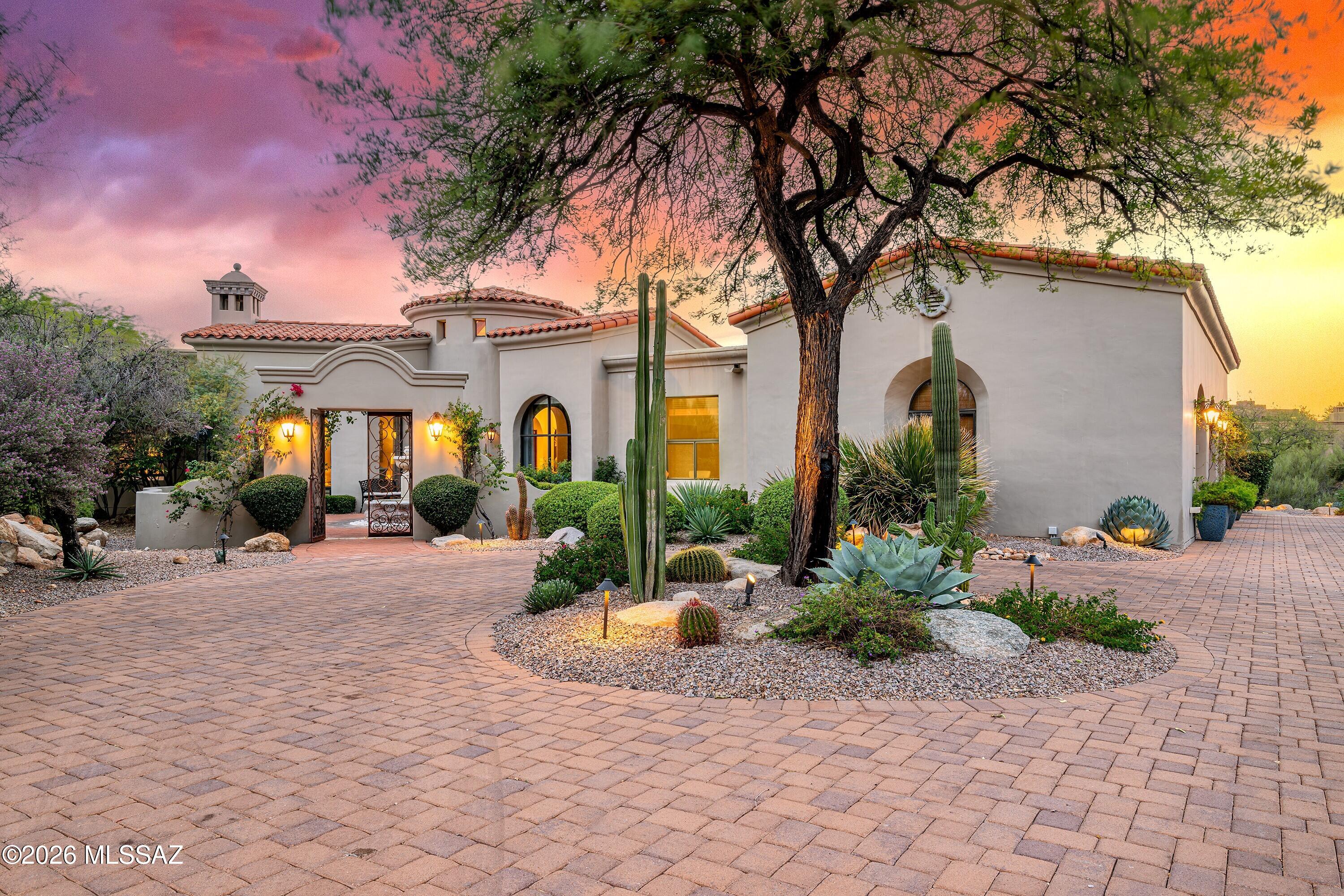 Located within the prestigious gated community of Pima Canyon Estates, one of Tucson's most exclusive and sought-after neighborhoods, this exceptional residence offers luxury living on a sprawling and private 1.31-acre homesite. Mature desert landscaping, elegant lighting, and an expansive paver driveway create a striking first impression. Beyond the private courtyard, complete with a tranquil fountain and custom metal gates, you'll discover a home that seamlessly blends timeless architecture with thoughtfully curated modern design. A dramatic rotunda foyer welcomes you inside, creating a graceful connection to the home's beautifully designed living spaces. At the heart of the residence is a spectacular, designer-renovated kitchen and great room that has been completely reimagined for today's lifestyle. This was far more than a cosmetic remodel; walls were removed and the floor plan thoughtfully reconfigured to create an expansive gathering space filled with natural light.
The chef's kitchen showcases custom floor-to-ceiling cabinetry, a Wolf gas cooktop, stainless steel Wolf wall oven, Wolf steam oven that also serves as a convection oven, solid porcelain backsplash, and a fully integrated Sub-Zero refrigerator concealed behind matching cabinetry panels. An oversized porcelain island with Dekton solid surface countertops features a distinctive built-in dining area, creating the perfect setting for casual meals, entertaining, or everyday living.
The adjoining great room is rich in architectural character with hand-hewn corbel beams, classic herringbone brick flooring, an impressive fireplace and dramatic walls of glass that frame breathtaking views of the sparkling pool, tranquil water feature, and Tucson's twinkling city lights beyond. Every living space has been thoughtfully designed to embrace the surrounding natural beauty while maintaining a warm, inviting atmosphere. A professionally integrated whole-home audio system delivers exceptional sound throughout the residence, with built-in speakers serving the great room, kitchen, living room, family room, primary suite, and multiple outdoor entertaining spaces, including dedicated zones for both the covered dining terrace and poolside lounge.
The elegant den is anchored by a handsome stone fireplace and highlighted by a dramatic arched window that perfectly frames the Catalina Mountains. Overlooking the lush courtyard, the formal dining room offers an ideal balance of sophistication and comfort for intimate dinners and gatherings.
A thoughtfully designed split-bedroom floor plan provides exceptional privacy. The primary suite is enhanced by a striking designer accent wall featuring a richly textured wallcovering with the look of natural crushed stone and mineral aggregate. Inspired by the timeless appeal of terrazzo, its warm taupe palette creates subtle movement, and dimension that elevates the room with understated luxury. A two-way fireplace shared with the spa-inspired bathroom, a soaking tub, separate walk-in shower, generous walk-in closet, and direct access to the backyard.
Designed to embrace Arizona's exceptional outdoor lifestyle, the backyard is equally impressive. The pool and spa interior finish is complemented by vibrant blue pebbles and premium shimmering sea enhancements, creating an inviting, resort-inspired light blue water color and sparkle. The illuminated water feature overlooks the lush Sonoran Desert, sparkling city lights, and Tucson's unforgettable sunsets. The expansive covered veranda is designed for year-round entertaining with a stone gas fireplace, outdoor kitchen, built-in BBQ, a quality stainless steel refrigerator, and generous seating and dining areas all perfectly positioned to capture the surrounding mountain views.
Ideally located in the heart of the Catalina Foothills, this remarkable property is just minutes from premier hiking trails, the shops and restaurants of Casas Adobes and La Encantada, La Paloma Country Club, and many of Tucson's finest dining and recreational destinations. Offering exceptional craftsmanship, thoughtfully curated finishes, and one of the Foothills' most desirable locations, this is a rare opportunity to own an extraordinary home in Pima Canyon Estates.