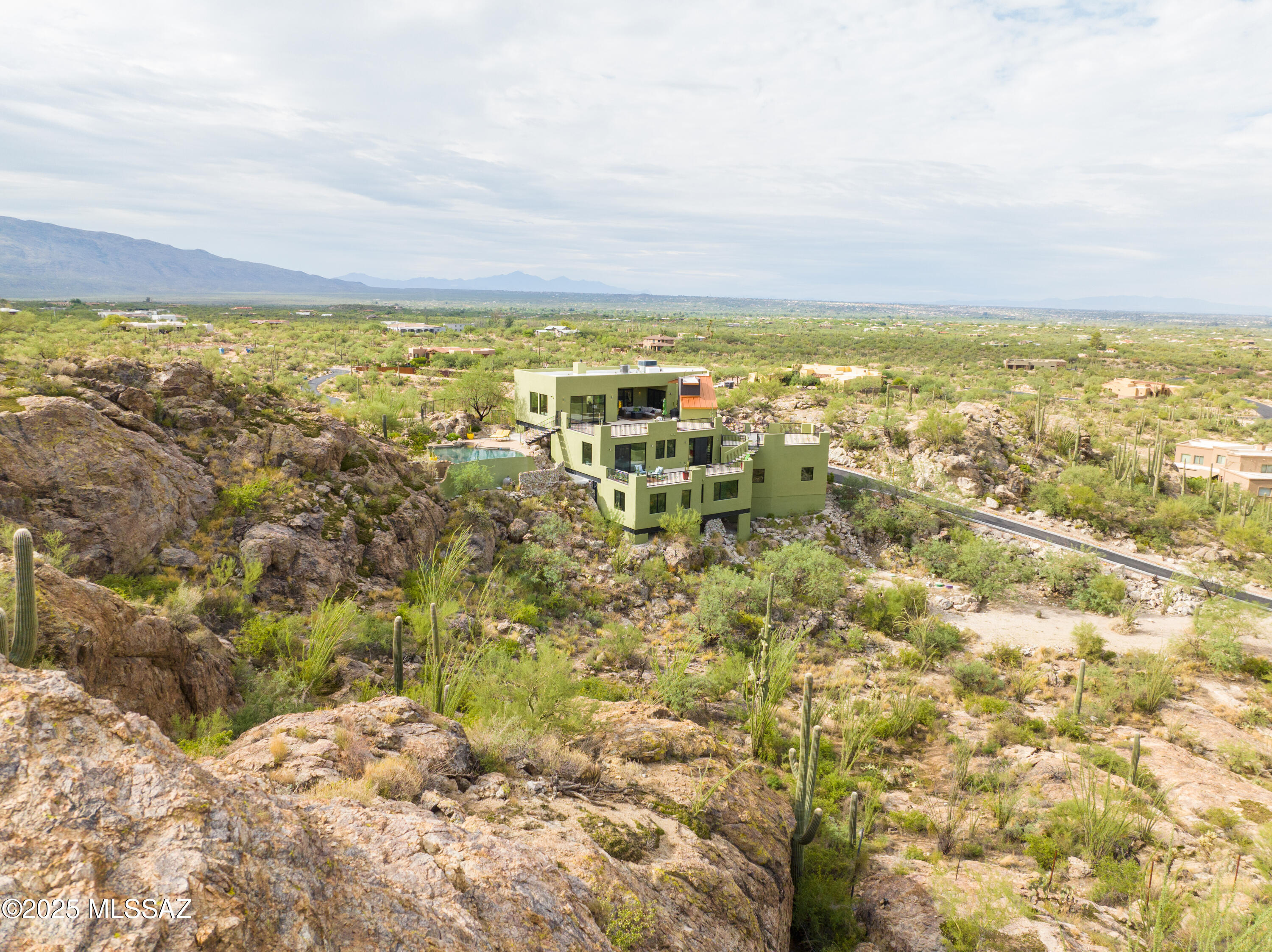 Hilltop Masterpiece with 360° Desert & Mountain Views. This is An Elevated Lifestyle with Endless Views!! Welcome to your extraordinary 3.31-acre hilltop estate delivering the ultimate in luxury desert living. Completely reimagined from top to bottom, this one-of-a-kind custom home offers elegance, privacy, and an unparalleled connection to the surrounding natural beauty. From the resort-style infinity-edge pool, artfully built into the mountainside and framed by natural rock formations, you'll feel completely at one with the desert. Sparkling water merges seamlessly with the horizon, creating an illusion that stretches into the sweeping desert scape. Surrounded by multiple decks and patios, the pool becomes the centerpiece of outdoor living--perfect for daytime relaxation, sunset gatheri or starlit evenings under Tucson's brilliant desert skies. Come inside and you'll find sophisticated upgrades at every turn. The home has been fully renovated with new stucco, dryvit, paint, decks, windows, doors, roof, plumbing, and electrical. Interiors showcase solid hardwood floors, plush carpet, custom cabinetry, and sleek quartz counters. The chef's kitchen is a dream with Thermador appliances, 6-burner gas stove with pot filler, double oven, and bi-fold accordion doors that seamlessly open to the outdoors. The thoughtfully designed floorplan spans three levels, connected by both stairs and Your own private elevator. The top floor hosts open living spaces, dining, kitchen, and guest bath, while the middle floor is devoted to the luxurious primary suite with walk-in closet, spa-like bath, office, laundry/half bath, and media room. The ground level features two spacious guest bedrooms, full bath, and utility roomideal for family or visitors. Set within a gated community with its own private gated drive, this estate blends security with serenity. Outdoor living is elevated with expansive decks for sunrise coffee, sunset dining, or stargazing under Arizona's brilliant night skies. An oversized 3-car garage provides ample storage, while proximity to two prestigious country clubs, premier shopping, fine dining, and excellent schools ensuring convenience without sacrificing privacy. This property is more than a home, it's a retreat, a statement, and a lifestyle. Experience the peak of Tucson luxury living.