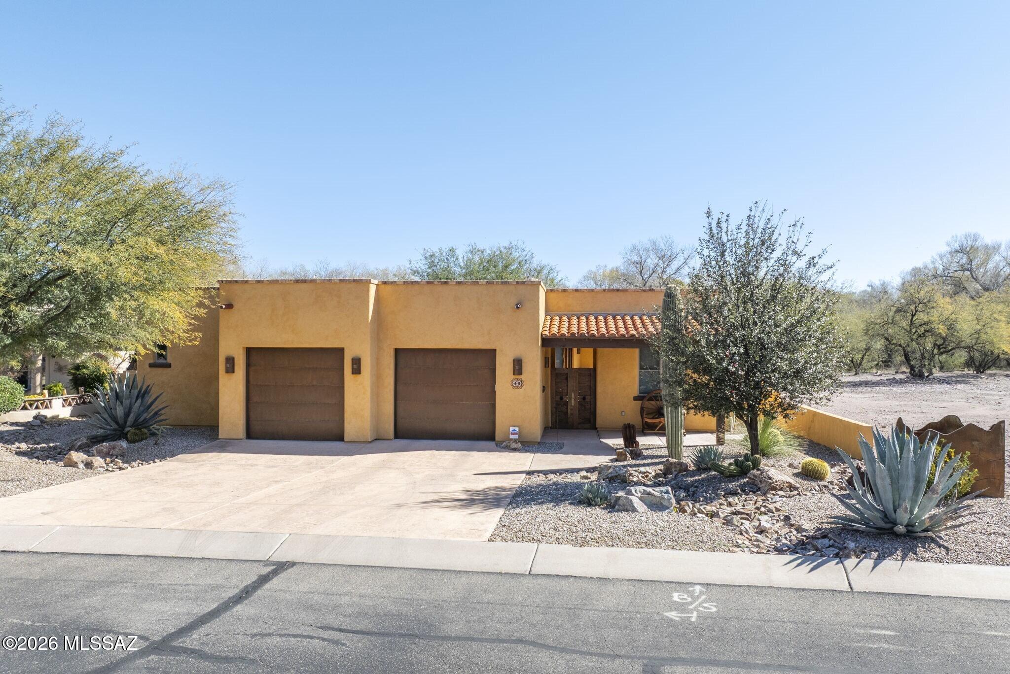 Nestled alongside the Anza Trail in Tubac's desirable Barrio Santiago neighborhood, this stunning three-bedroom, three-bath home is custom-built and meticulously crafted to blend into its natural setting. Walled courtyard offers privacy for covered and open terraces, perfect for al fresco entertaining. You'll find custom tilework and mesquite design details throughout the home's interior. Dramatic open-concept circular gathering room features elegant iron chandelier and cozy kiva fireplace. Entertainer's kitchen features an apron-front sink, seated bar and generous walk-in pantry. The owner's retreat features direct terrace access, walk-in closet and en suite bath. A detached studio with the property's fourth bathroom is ideal for private guest house, home office, workshop or hobby space.