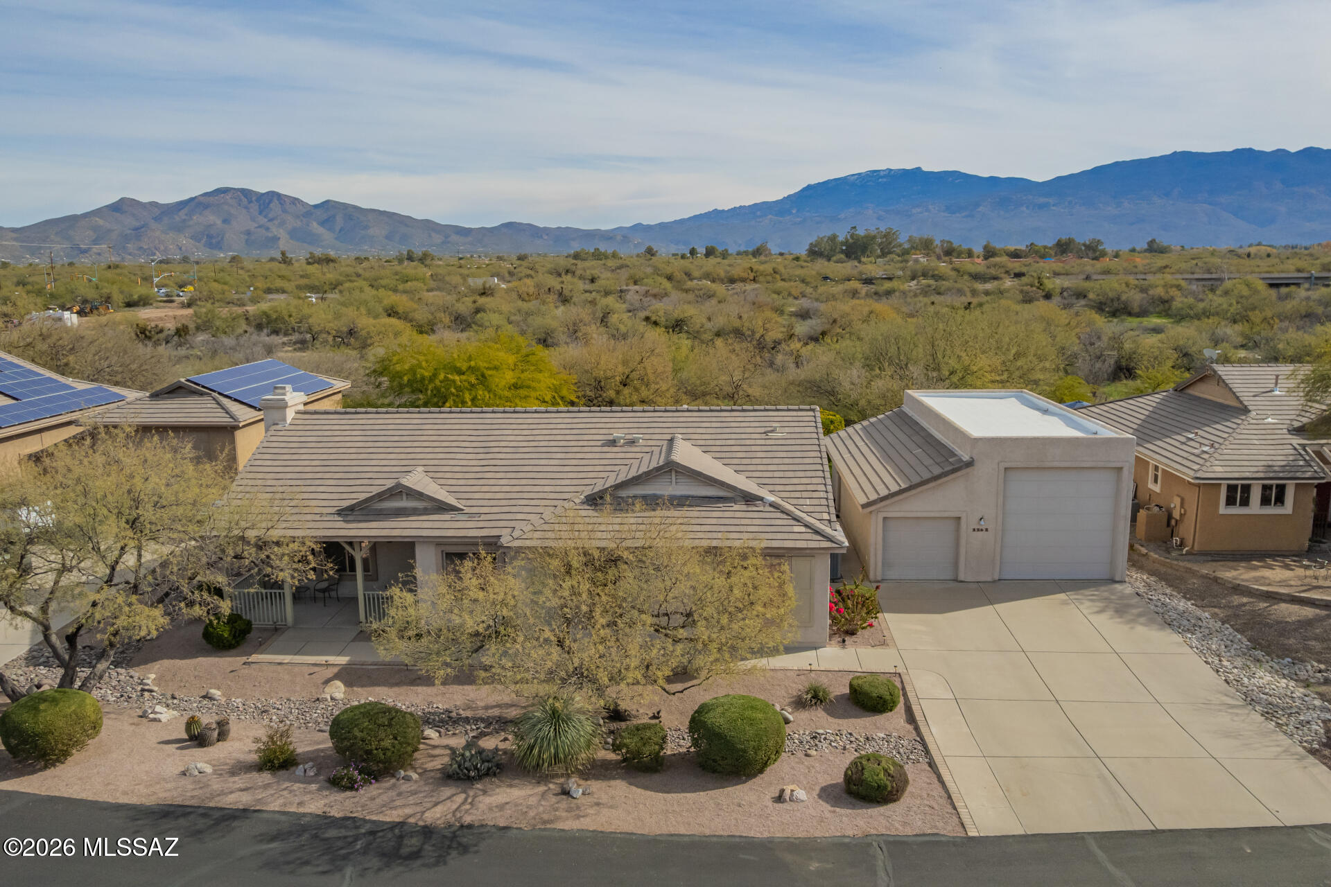 Beautifully situated on a quiet cul-de-sac with stunning mountain views, this home welcomes you with desert landscaping, a charming front porch, and an extended driveway leading to a detached car/RV garage. Vaulted ceilings and abundant natural light highlight the open great room with fireplace and easy flow to the main living areas. The immaculate kitchen features maple cabinetry, laminate countertops, stainless steel appliances, recessed lighting, pantry, and breakfast bar. A third bedroom with French doors offers flexible use as an office or guest room. The primary suite includes mirrored closets and a private bath with dual sinks, separate tub, and shower. Enjoy an oversized backyard with covered patio, fenced pool/spa, and fire pit in a park-like setting.