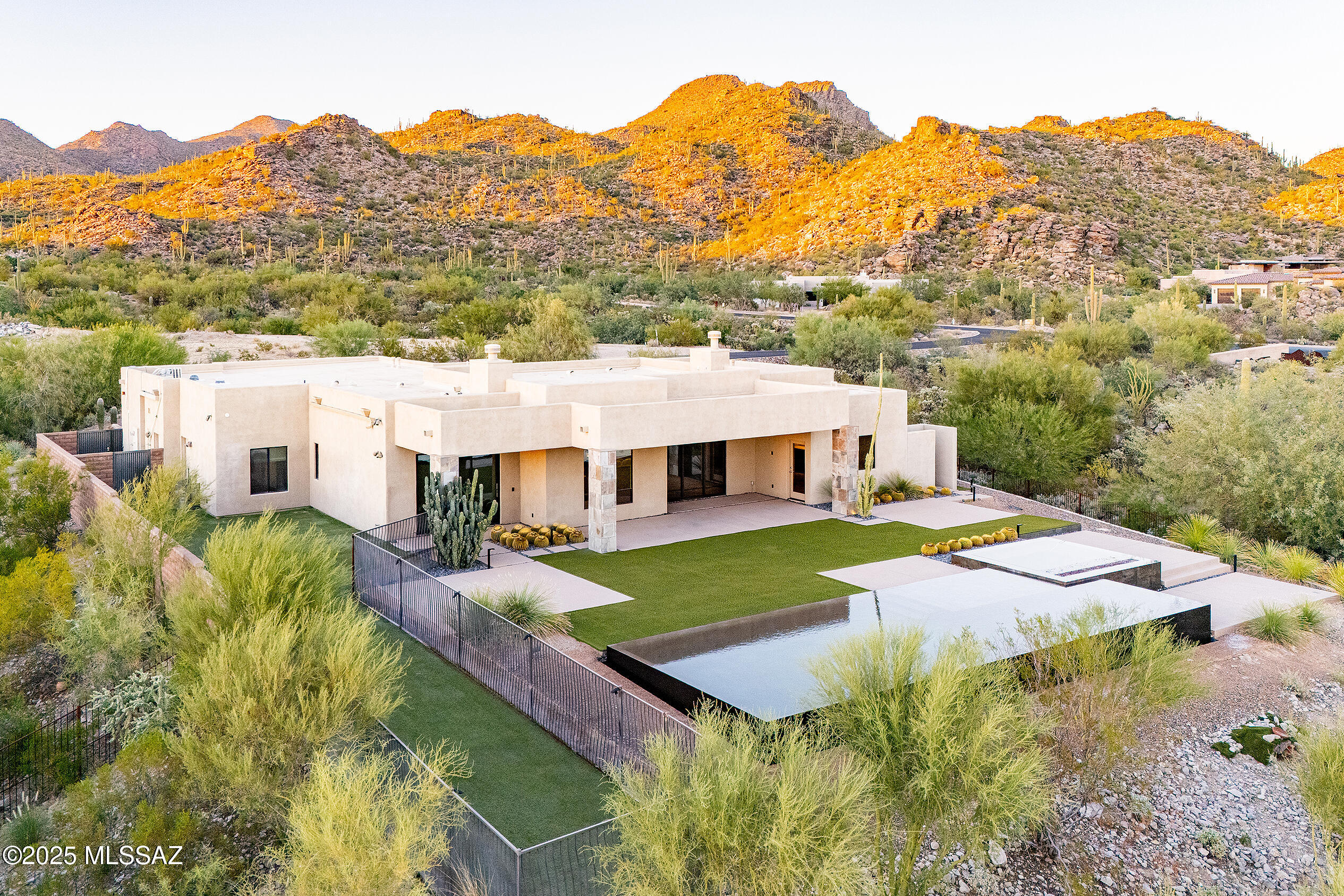 Sleek California Contemporary in Prestigious Canyon Pass at Dove Mountain. Welcome to ultra-contemporary desert living in one of Dove Mountain's most sought-after gated communities—Canyon Pass. This architecturally striking ranch-style home blends modern elegance with breathtaking natural surroundings. Step through the private entry gate and past tranquil fountain features, leading to a spacious, light-filled interior. A dramatic wall of windows immediately draws your eyes to panoramic views of the Tucson skyline, showcased beyond the stunning negative-edge pool and spa. Designed for entertaining, the expansive great room seamlessly connects to a gourmet chef's kitchen featuring a large island, premium appliances, and an open-concept dining area—all centered around a cozy gas fireplace The split-bedroom floor plan offers privacy and comfort with two generous ensuite bedrooms on the east wing--one with its own private exterior entrance, ideal for guests or multigenerational living. The luxurious primary retreat includes a second gas fireplace, wall-to-wall windows with serene backyard views, a spa-inspired bath, and an oversized walk-in closet. Additional highlights include a stylish powder room, a spacious 2-car garage with extra storage, and high-end finishes throughout. This is refined desert living--where contemporary design meets exceptional views in an exclusive, guard-gated setting. The home was built by Dove Mountain Homes, pool was designed and built by Azure Gallery run with a Pentair app with multicolored lights and a traditional heated chlorinated system and outdoor shower. plus a Crestron outdoor audio system installed and managed by Automation Specialists in Tucson