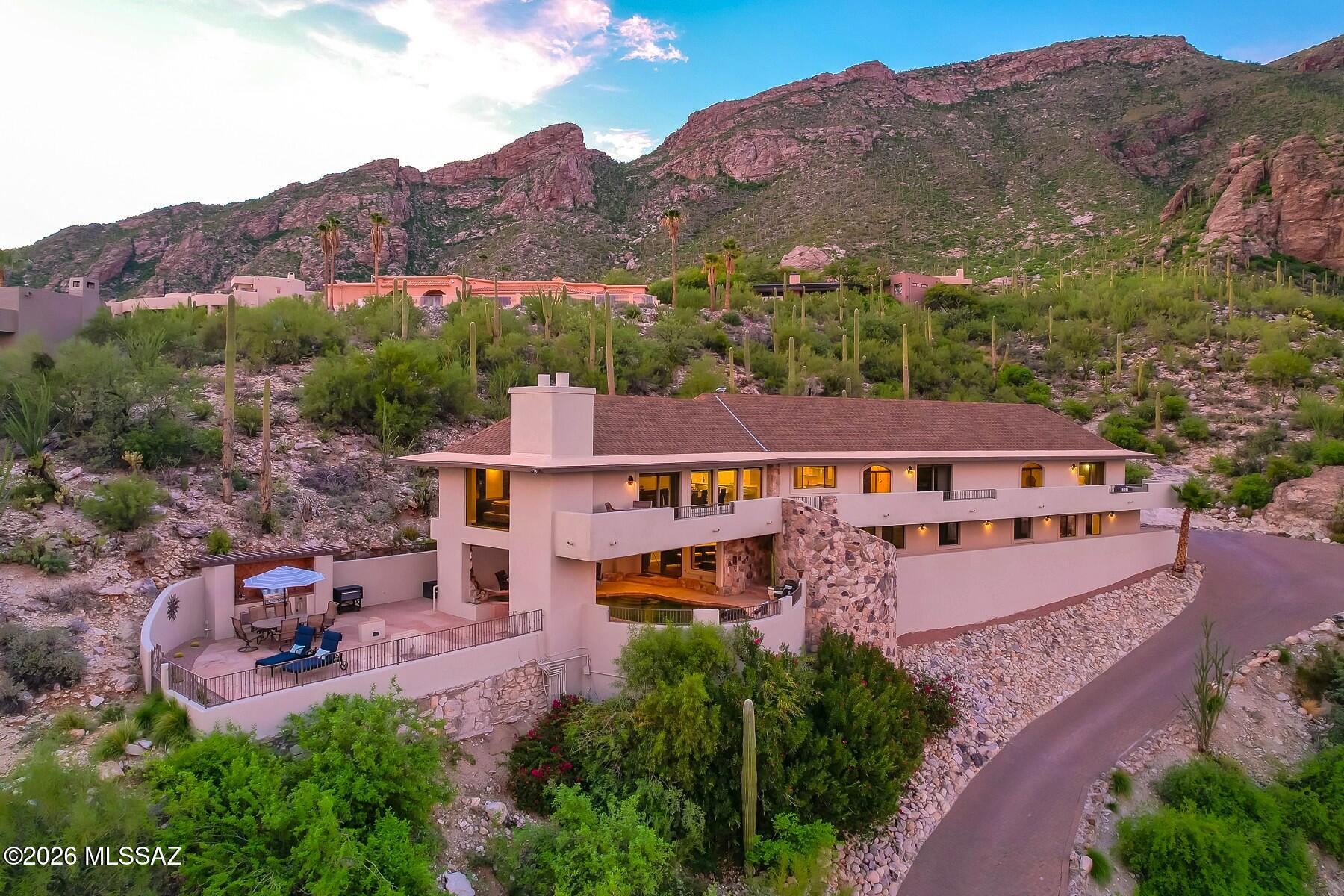 Skyline Country Club Estates offers this rare opportunity to own one of Tucson's most dramatic hillside residences. Carved into the desert foothills beneath the granite cliffs of the Catalina Mountains, this exceptional 4,793 sq. ft. home commands breathtaking panoramic views across the entire Tucson Valley from expansive wraparound view decks. One-of-a-kind Architectural gem w/ rugged native stone accent walls blending seamlessly w/ the natural surroundings, creating timeless high-desert character. Professionally remodeled chef's kitchen... premium appliances, custom cabinetry, multiple breakfast bars & stunning granite countertops. Fantastic lower-level Family Room is Entertainer's dream w/ fully outfitted sports-bar and direct access to the creatively shaded Pool /Spa/BBQ/ View decks.