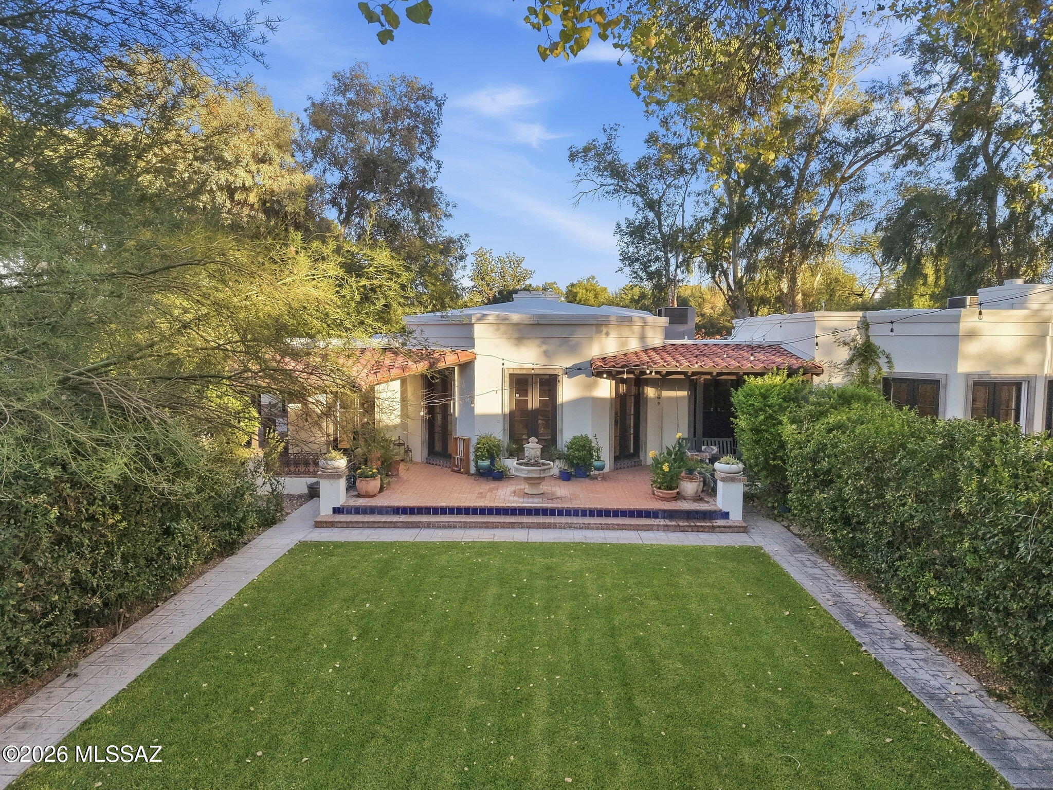 A rare design-driven estate in Tucson Country Club, this reimagined residence blends classic Tucson architecture with the ease of contemporary living. Set behind mature trees and botanic garden-like grounds, the property has the feeling of a private resort villa, with red-tile rooflines, white stucco forms, shaded verandas, brick courtyards, sculptural garden moments, and a sequence of outdoor rooms connected by intimate garden paths.
The main house has been thoughtfully renovated throughout, with a new layout, updated bathrooms, refreshed interiors, and a more natural flow for everyday living and entertaining. Also, roof has been completely resurfaced, new plumbing & electrical, generator installed & electric car power connection installed. Formal and informal spaces balance elegance with warmth, including a gracious living room, open kitchen and great room, office, sitting room, and a primary suite connected to the home's garden-centered rhythm.
The property's 3,738 square feet include a 2,880-square-foot main house, a 659-square-foot guest casita, and a 199-square-foot studio/exercise space. This gives the home unusual versatility for hosting, extended stays, creative work, wellness, or separate guest accommodations, without compromising the intimacy of the main residence.
Outdoor design includes covered patios, shaded dining areas, a screened patio, pool and spa, lawn, mature trees, and quiet seating moments create a resort-like sense of privacy in one of Tucson's most established enclaves.
For a buyer with a strong design sensibility, this is a home defined by architecture, gardens, texture, privacy, and a true sense of place.