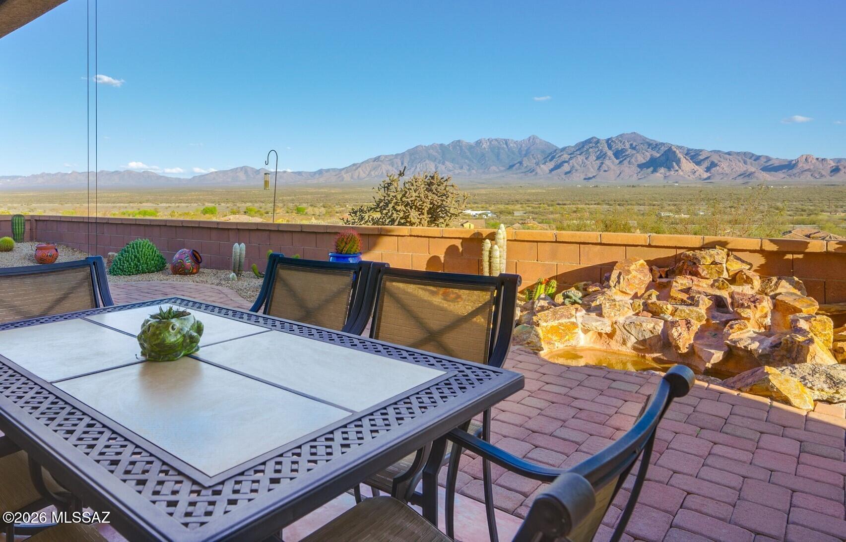 Step into the epitome of retirement luxury, where elegance meets the serene beauty of Southern Arizona's landscapes. This exquisite home is tailor-made for those seeking a peaceful retreat without compromising on style and comfort.  The allure begins at the threshold, where a breathtaking view of the Santa Rita Mountains unfolds before you, framed by an impressive wall of windows that invite the beauty of the outdoors in. The charm of this space is enhanced by a delightful banquette, perfectly positioned to offer both functionality and finesse. The open-concept design masterfully choreographs the spellbinding mountain views as your constant backdrop, whether you're preparing delectable dishes in the creatively designed kitchen--with its center island and casual eating nook--or hosting a special dinner in the spacious dining area, seamlessly integrated with the great room.  Luxury extends to the generously-sized primary suite, where the mountain vistas are showcased through expansive windows adorned with sophisticated plantation shutters. Revel in the sanctuary of the ensuite bath, boasting a split vanity, an indulgent walk-in shower, and ample closet space for a life well-organized.  Step outside to an oasis of tranquility, your personal slice of the great outdoors with unobstructed views of the desert's grandeur and multiple mountain ranges. The soothing sounds of a waterfall set the stage as you enjoy awe-inspiring sunsets with the sky transforming into a canvas of vibrant hues, celebrating the end of each day. Located in a gated community designed specifically for Southern Arizona retirees, this residence transcends mere living--it represents a lifestyle of opulence and serenity. Here, each day unfurls as a fresh opportunity to savor life --a lifestyle statement set against the breathtaking artistry of natural splendor.