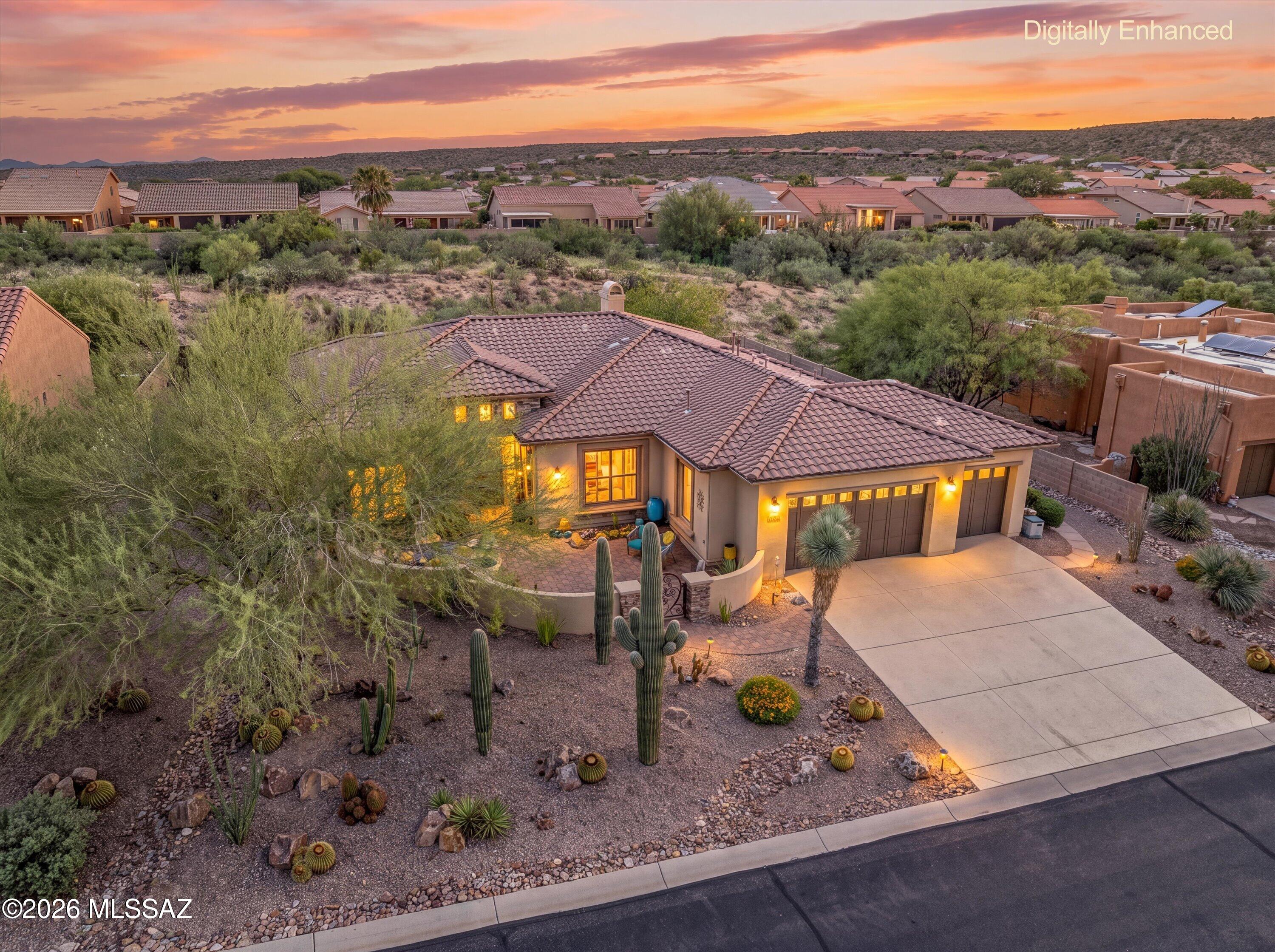 Striking curb appeal, highlighted by saguaros, welcomes you to the private courtyard of this Sabino model. Set on a prime lot in SaddleBrooke Preserve, the home offers exceptional indoor-outdoor living for residents and guests alike. Double decorative iron screens reveal an elegant iron-and-glass entry door, while a neutral palette and large-format tile create a graceful transition into the great room, designed for dining and effortless entertaining.  A stacked-stone fireplace provides a striking focal point, while large windows overlook the inviting Arizona Room, extended paver patio with Ramada. The open-concept island kitchen has abundant cabinetry, granite countertops, and premium stainless-steel appliances. An adjoining morning room with built-in wine and beverage refrigerators and large windows framing the courtyard and mountain views. The primary suite features a bay window and a spa-inspired en-suite bath with a walk-in tile shower, dual vanities, a soaking tub, and a walk-in closet. Guests enjoy the privacy of their own en-suite retreat. The ideally situated den/office offers beautiful built-in cabinetry and abundant storage. A three-car garage, spacious laundry room and convenient powder room add to the home's thoughtful amenities.
Designed for gracious indoor-outdoor living, the Arizona Room offers the perfect setting for entertaining or quiet enjoyment of the SaddleBrooke lifestyle. Just beyond, an expansive paver patio, Ramada, and outdoor kitchen form a private resort-style setting for gatherings. With natural open space bordering the backyard, the property enjoys an added sense of serenity and seclusion, completing this exceptional home.