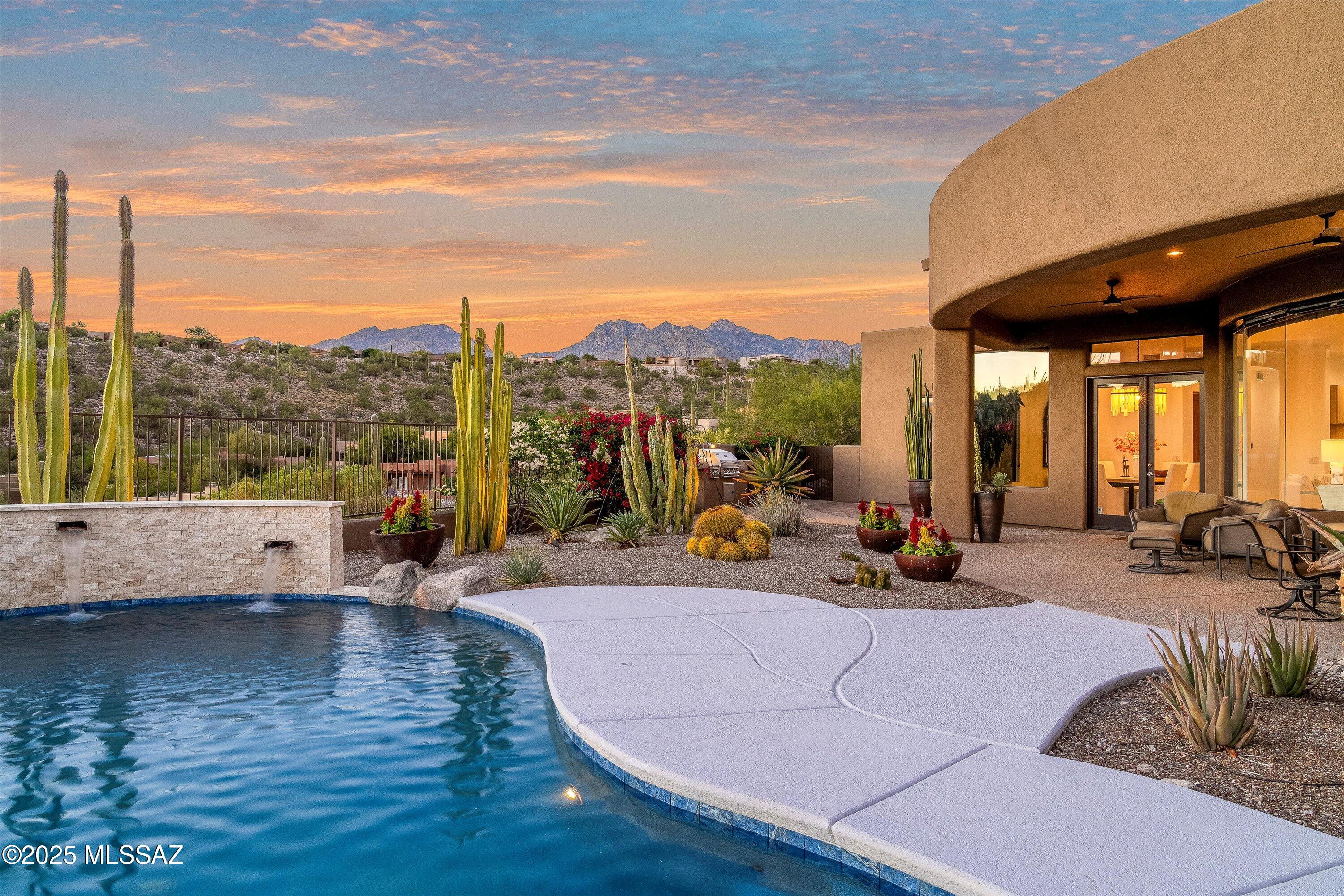 Welcome to your luxury contemporary oasis in the exclusive, gated Sabino Mountain community. The majestic cacti and custom iron door instantly set a dramatic tone. Step inside to an open-concept great room with soaring ceilings and a wall of curved glass that frames breathtaking, panoramic city lights and mountain views. This exquisite home boasts a newly remodeled chef's kitchen featuring custom textured modern slab cabinets, honed quartzite, and premium Wolf/Bosch/Sharp appliance suite, including induction cooking, convection/steam ovens, and a beverage refrigerator. Enjoy soft neutral colors, travertine flooring, designer automatic window treatments, and a cozy fireplace. Utmost privacy and resort-style entertaining is ensured by the remodeled, heated pool with a new finish and wate feature. Newer HVAC units (2024/2019) and an expansive 3 car garage complete this exceptional residence. Tucson Association of Realtors Home Tour Winner!