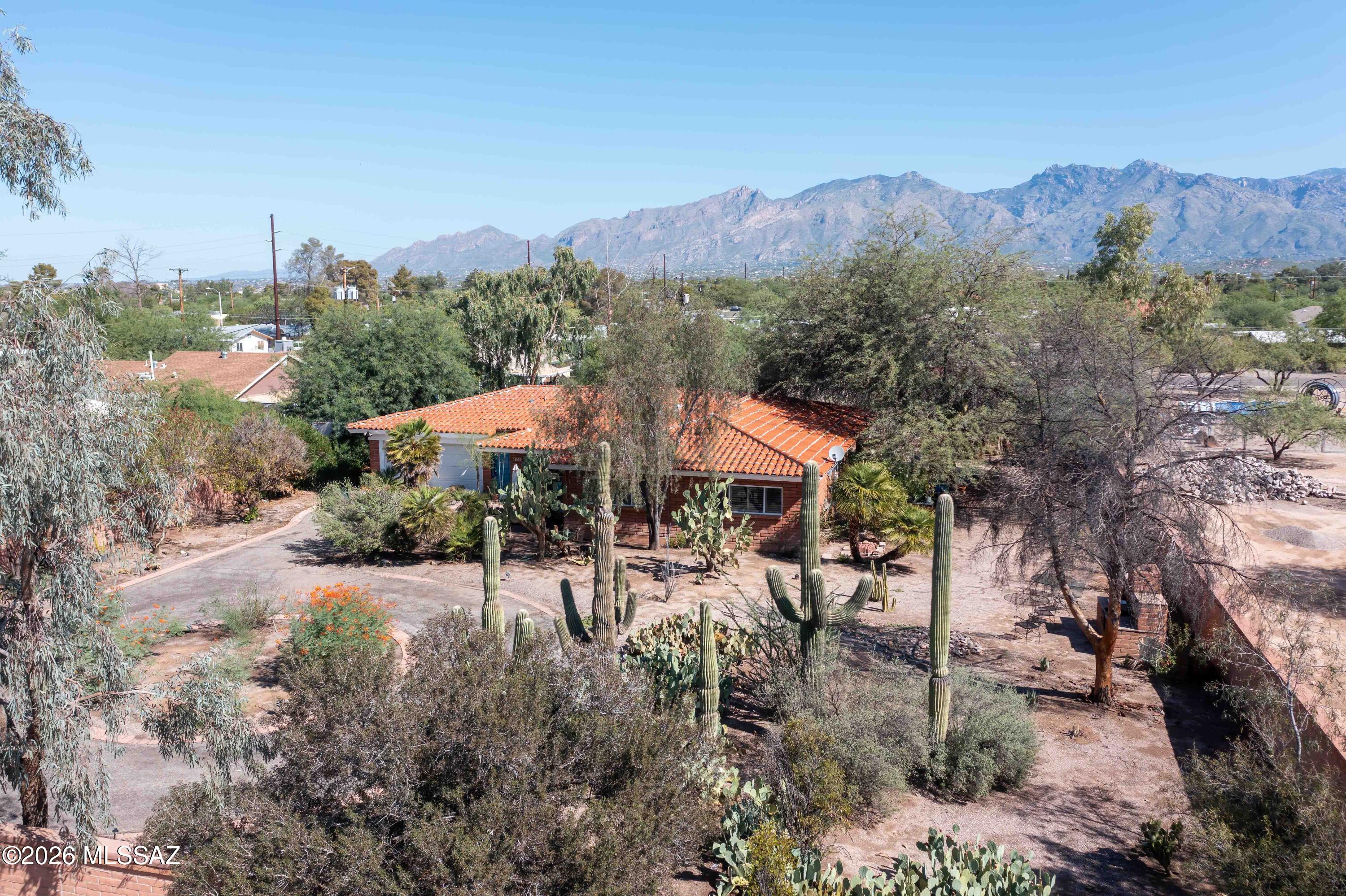 This is a very special property in central Tucson with stunning Catalina Mountain views on .87 acres that is fully walled.  Drive in through the tree lined driveway to a circular drive approaching this adobe built home.  A great spacious floorplan to make your own!  The 3rd bedroom connects to the second bathroom and offers a freestanding armoire that will convey in lieu of a built-in closet.  This room has its own private entrance and could also serve as a workspace/office.   All rooms are very spacious with lots of natural light.  Newer roof, HVAC and sewer line to city connection.  Fountains, plants and trails throughout property make this a potential oasis in close proximity to all your needed amenities.  Make an appointment to see today!
