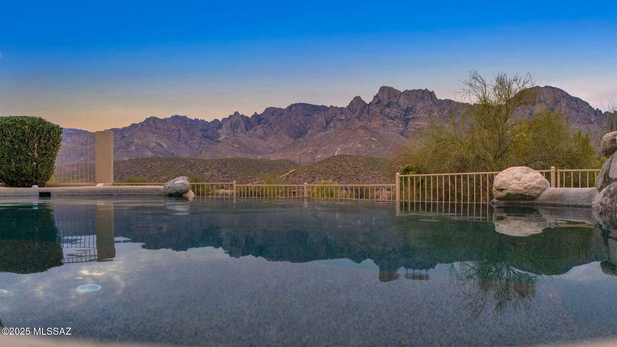 Open House Sat 3/8 11-2:30 Sun 3/9 12-3 Breathtaking Luxury Home with Panoramic Mountain & City Views
Welcome to The Palisades, where every arrival feels like an escape into serenity. As you drive through the gates, you are greeted by majestic mountain views that set the tone for the unparalleled beauty of this home. Perched high on a hill, this stunning 4-bedroom, 3-bathroom residence boasts the best views in the subdivision, offering full panoramic vistas of the Santa Catalina Mountain Range, twinkling city lights, and breathtaking sunsets.
Step inside and be captivated by the expansive great room, where large picture windows perfectly frame the mountains, creating a natural masterpiece in your everyday living space. A cozy fireplace and an intimate wet bar add warmth and elegance, making this the ideal place to unwind or entertain.
The gourmet kitchen is truly oversized, featuring an impressive island, a dedicated desk space, and a charming breakfast area. Adjacent to the kitchen, the formal dining room is a showstopper with custom cabinetry, a built-in wine rack, and a wine cooler, setting the stage for unforgettable dinner parties.

Designed for both comfort and privacy, the split floor plan offers three bedrooms on one side, along with a versatile community spaceperfect for a TV room, home office, or a tranquil library. The primary suite is a private retreat, where you can wake up to stunning mountain views and enjoy the ambiance of your own fireplace. The spa-like ensuite bathroom offers the space and luxury you deserve.
Step outside to experience true Arizona outdoor living. The expansive covered patio and open-air seating areas overlook a negative edge pool with a soothing water feature from the spaall set against an awe-inspiring natural backdrop. This is the view you've been searching fora home where luxury meets tranquility.
Don't miss this rare opportunity to own a dream home with unmatched views and unparalleled elegance.